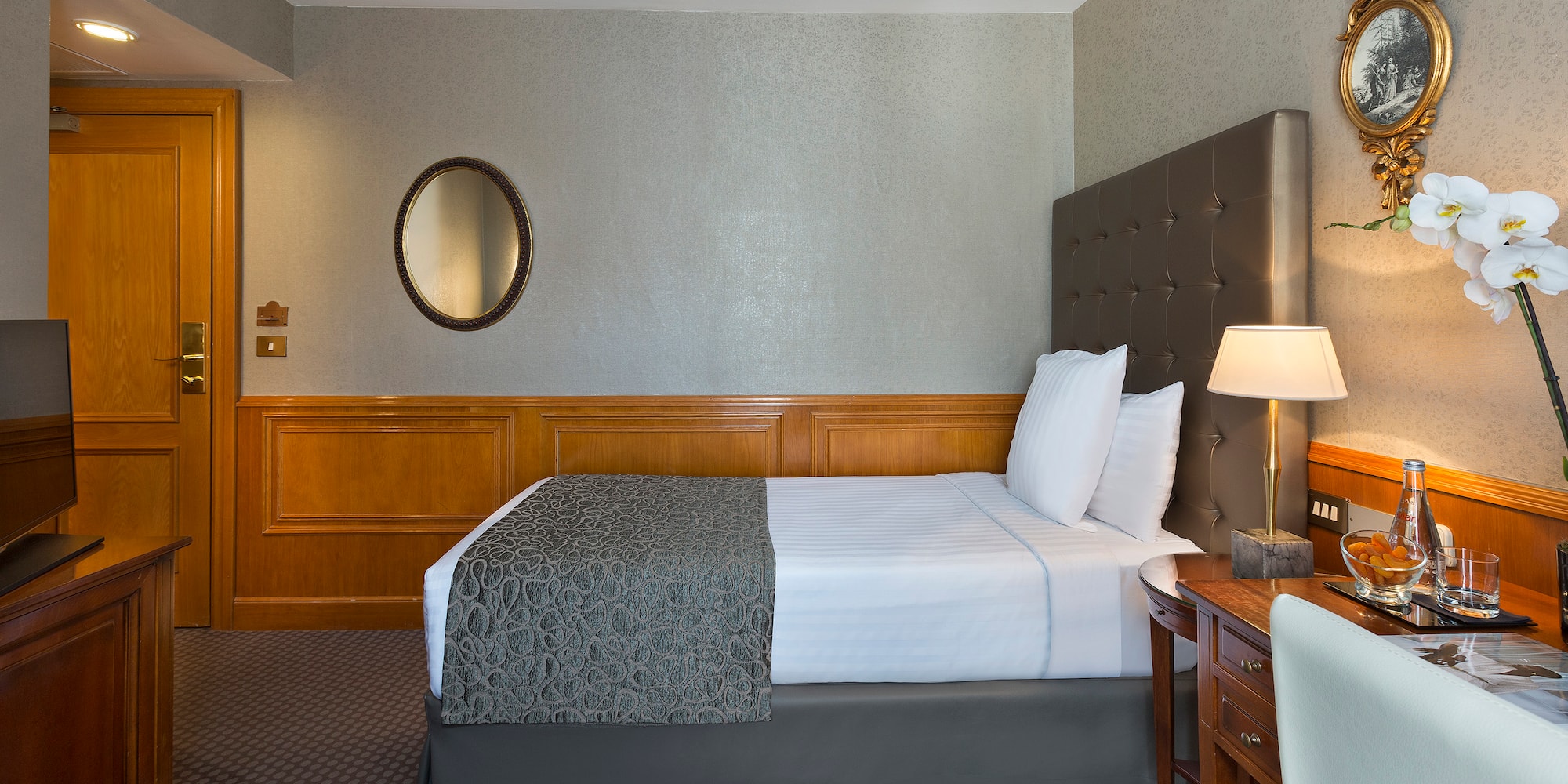 a bed with a lamp and a mirror