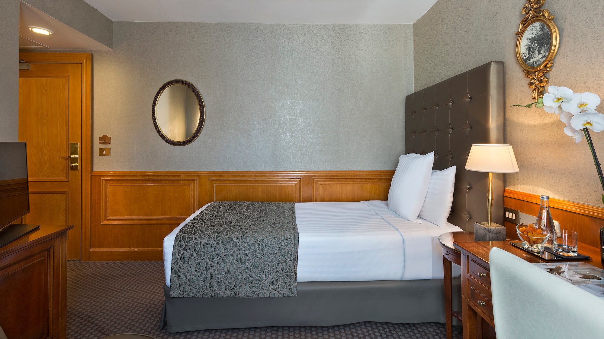 a bed with a lamp and a mirror