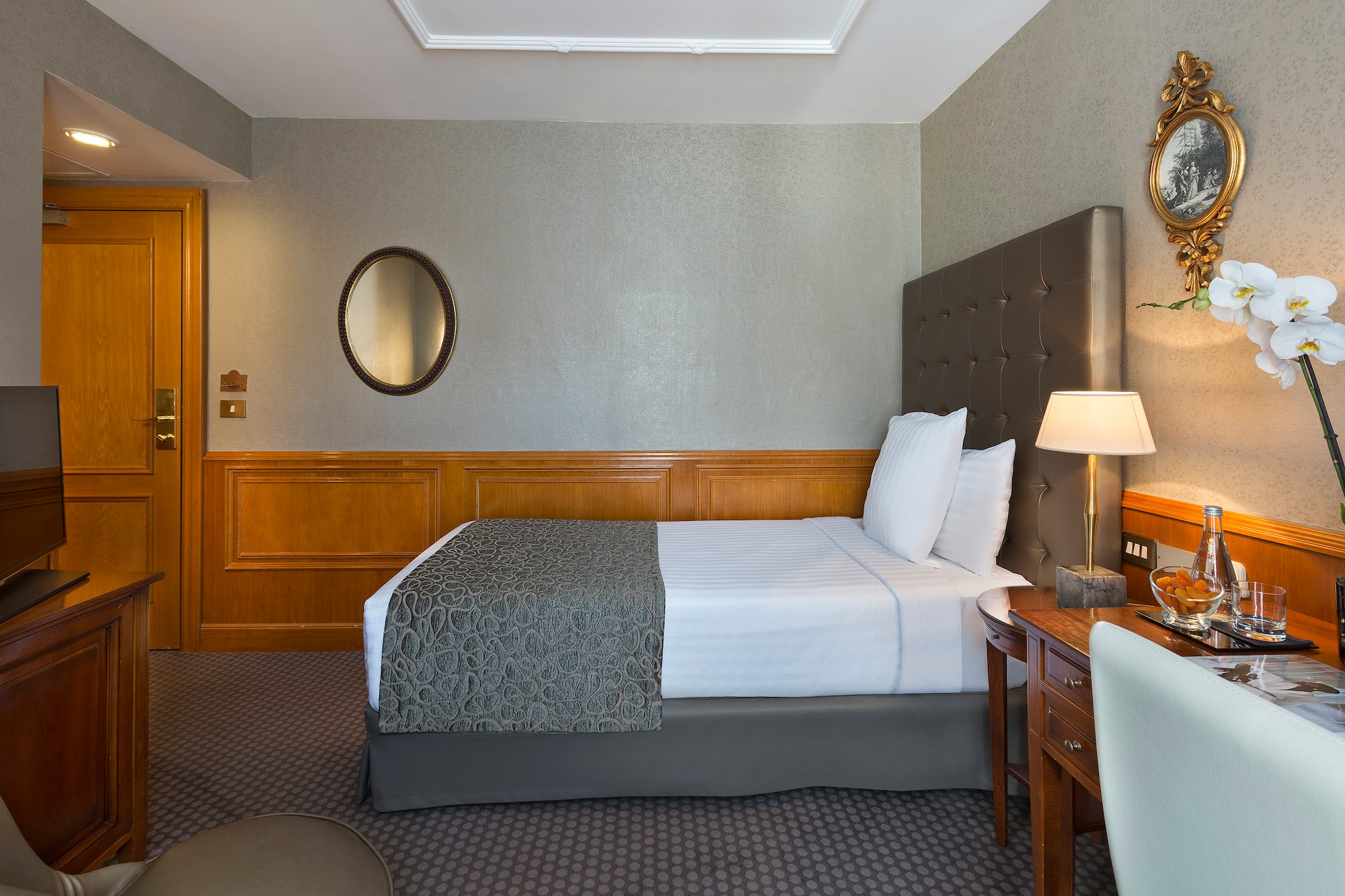 a bed with a lamp and a mirror