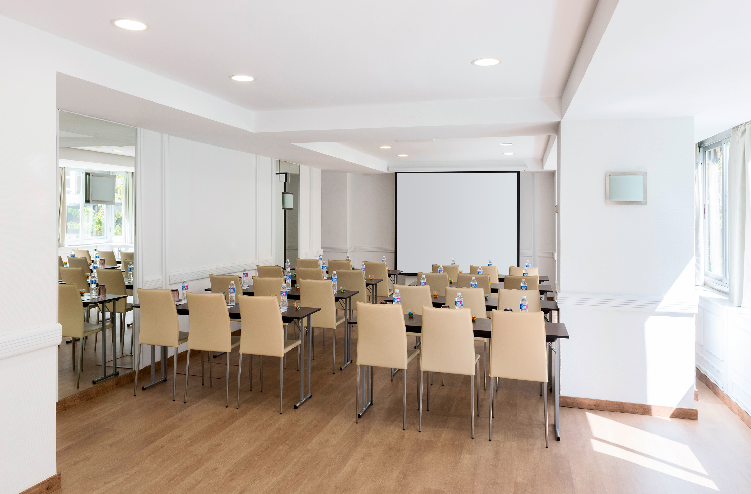 Bright modern meeting room with projection screen, beige chairs, and tables.