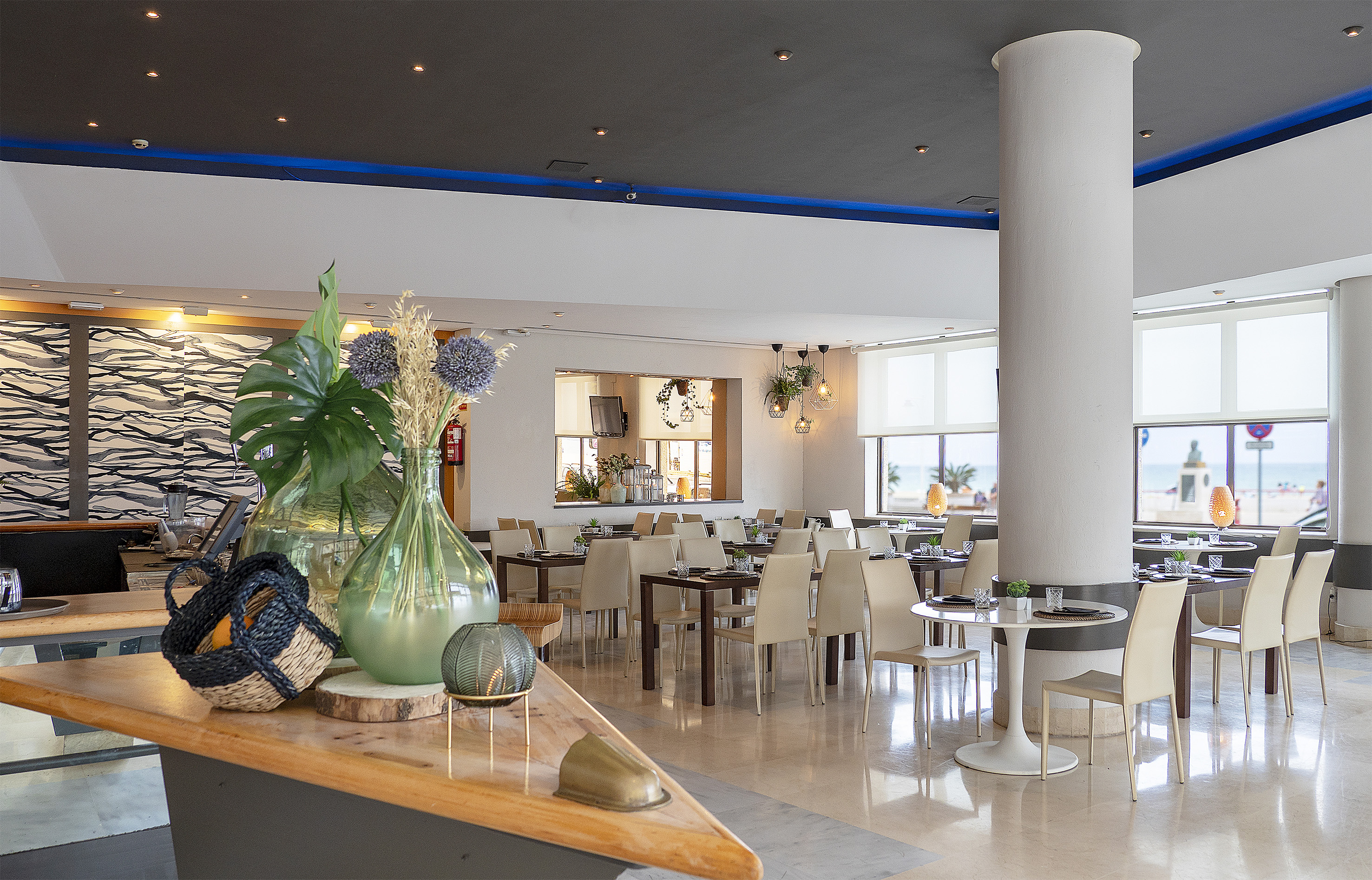 Modern restaurant dining room with seaside view and stylish tables.