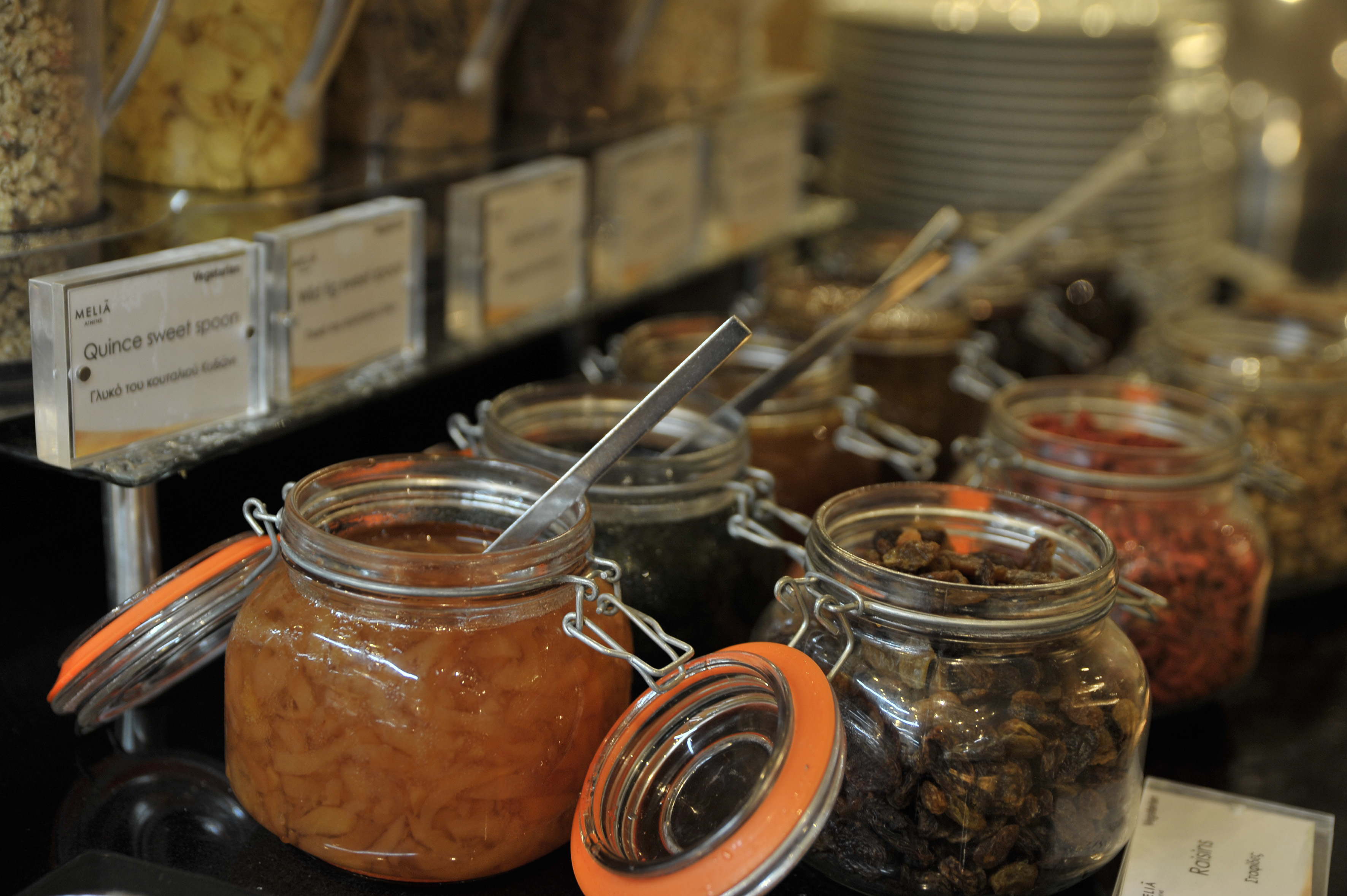 Quince sweet spoon and raisins in glass jars at a hotel breakfast buffet.