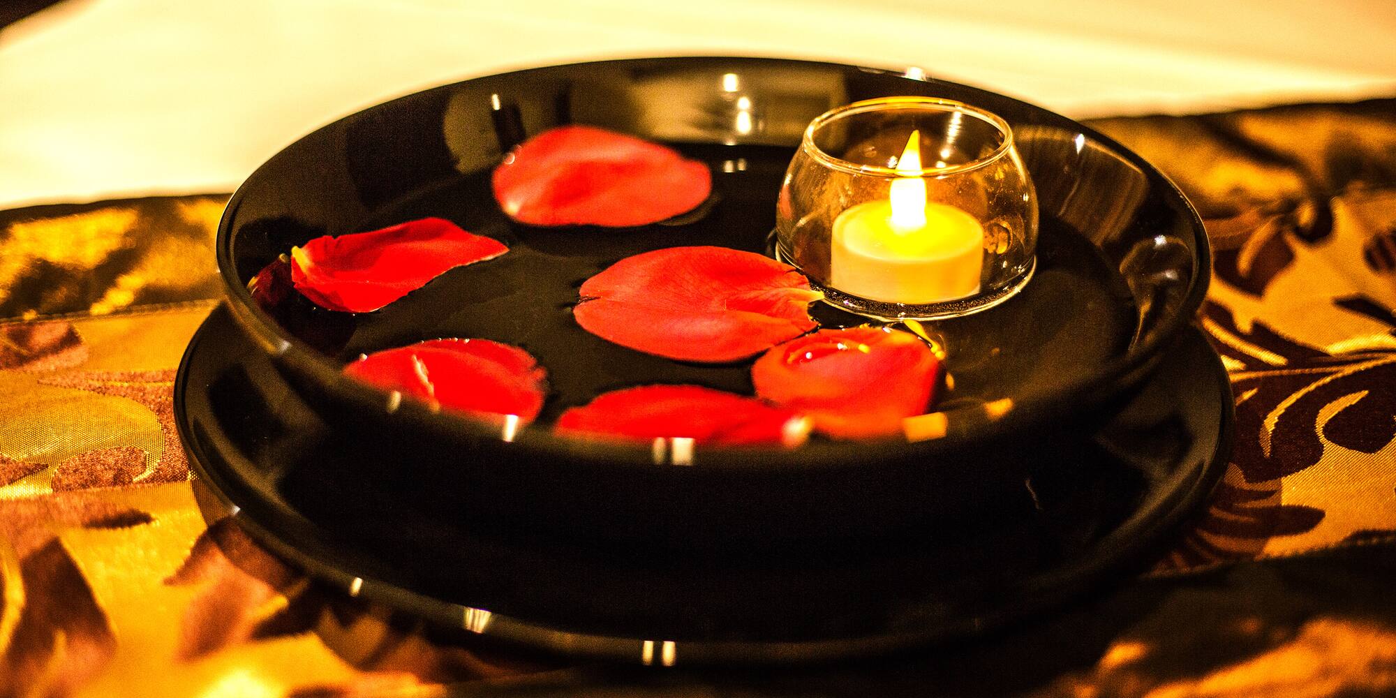 a plate with rose petals and a candle