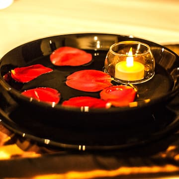 a plate with rose petals and a candle