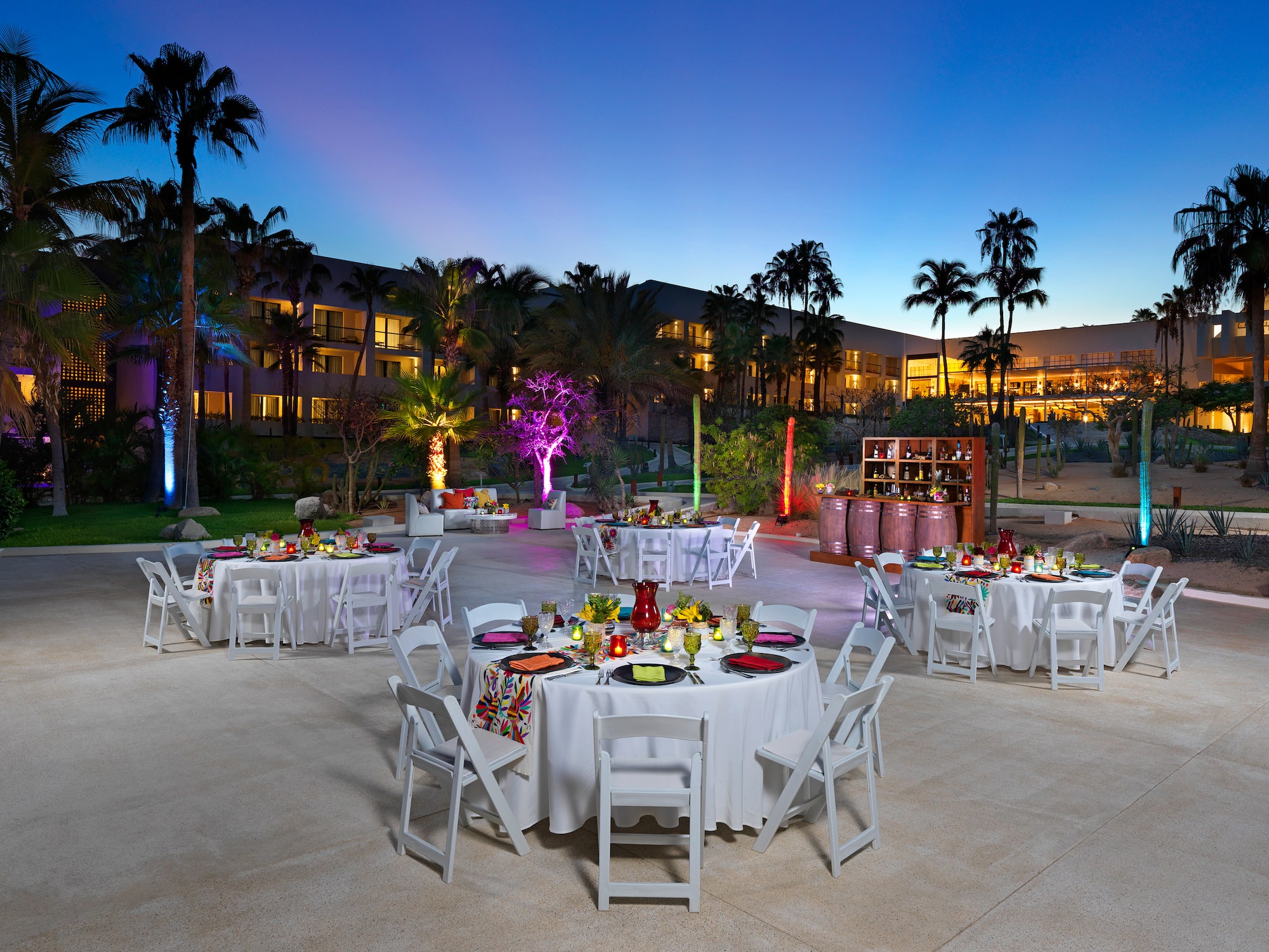 a group of tables and chairs outside with palm trees and lights