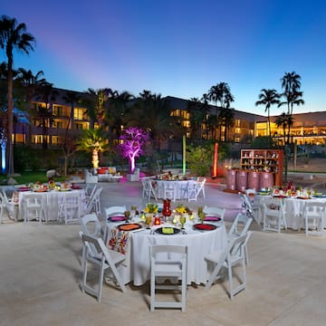 a group of tables and chairs outside with palm trees and lights