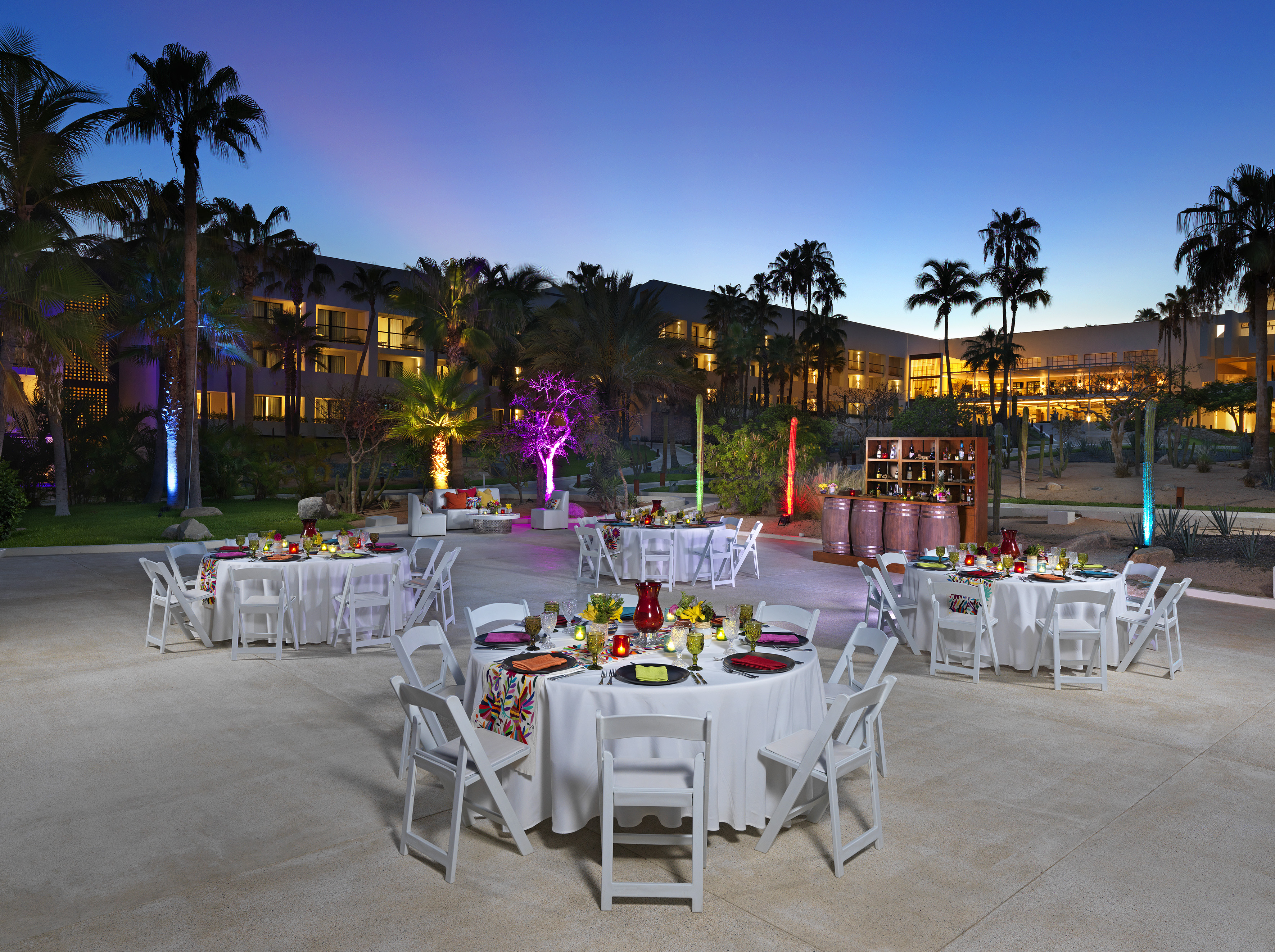 a group of tables and chairs outside with palm trees and lights