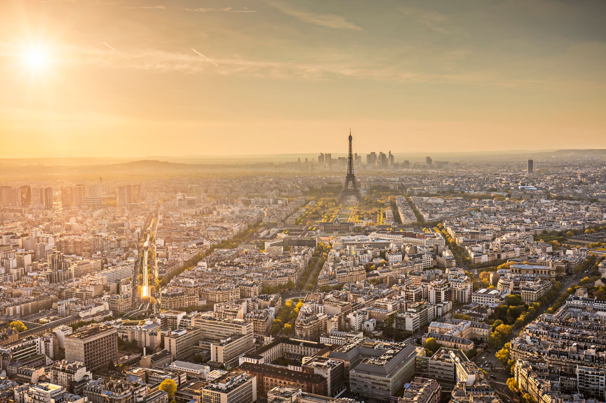 Vista aérea de París al atardecer con la Torre Eiffel y rascacielos.