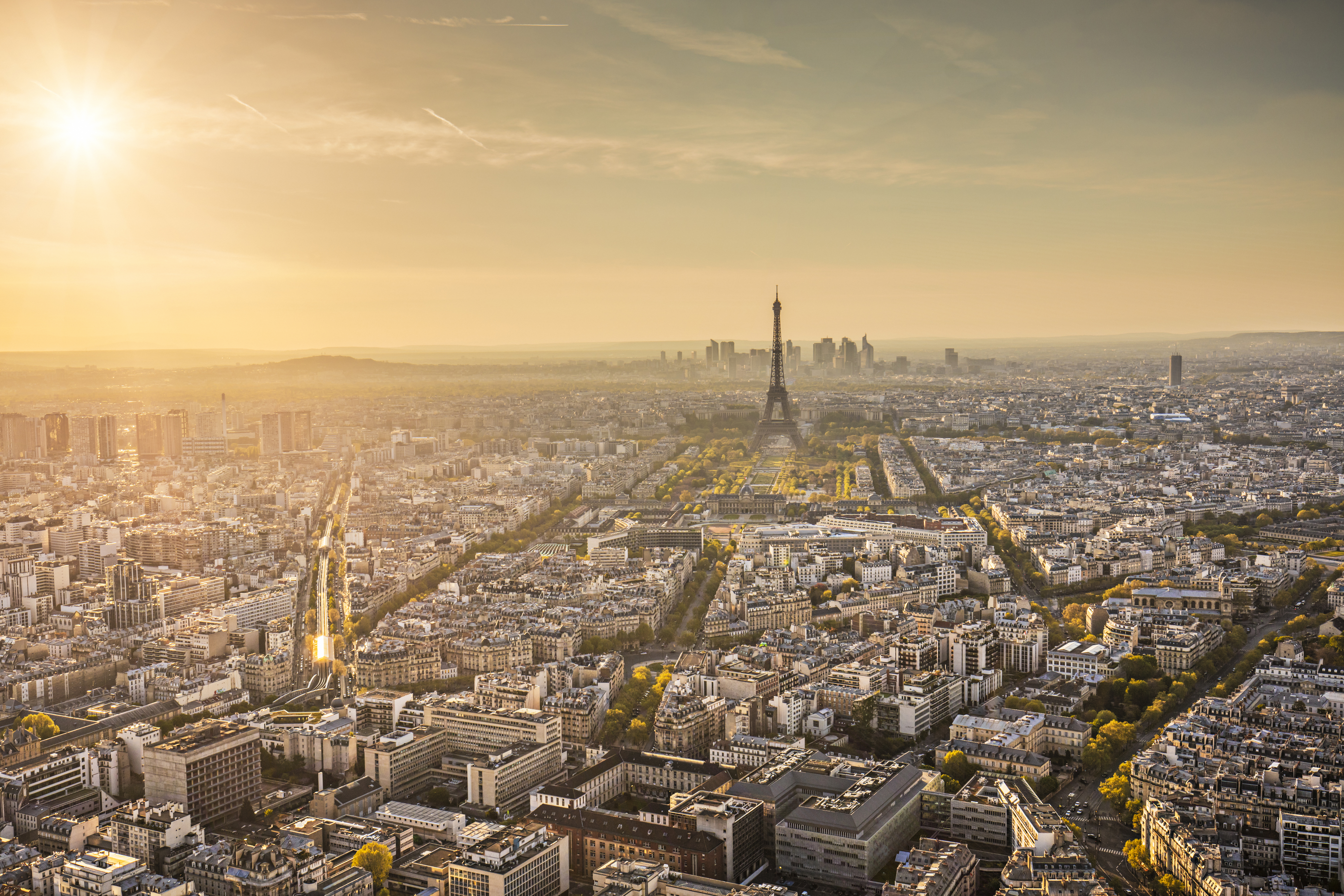 Vista aérea de París al atardecer con la Torre Eiffel y rascacielos.