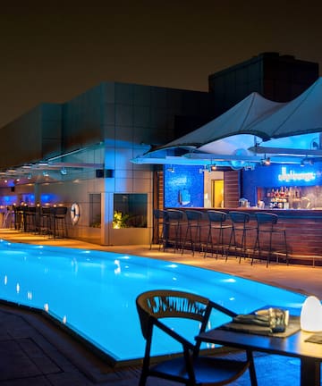 a pool with a bar and chairs at night
