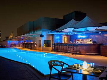 a pool with a bar and chairs at night