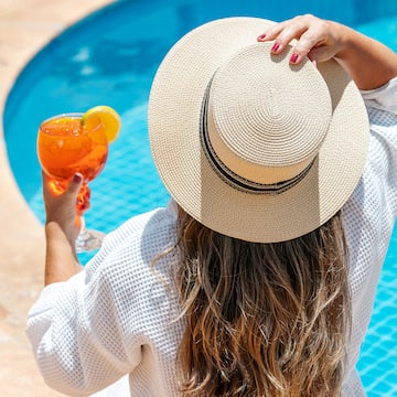 a woman wearing a hat and holding a drink