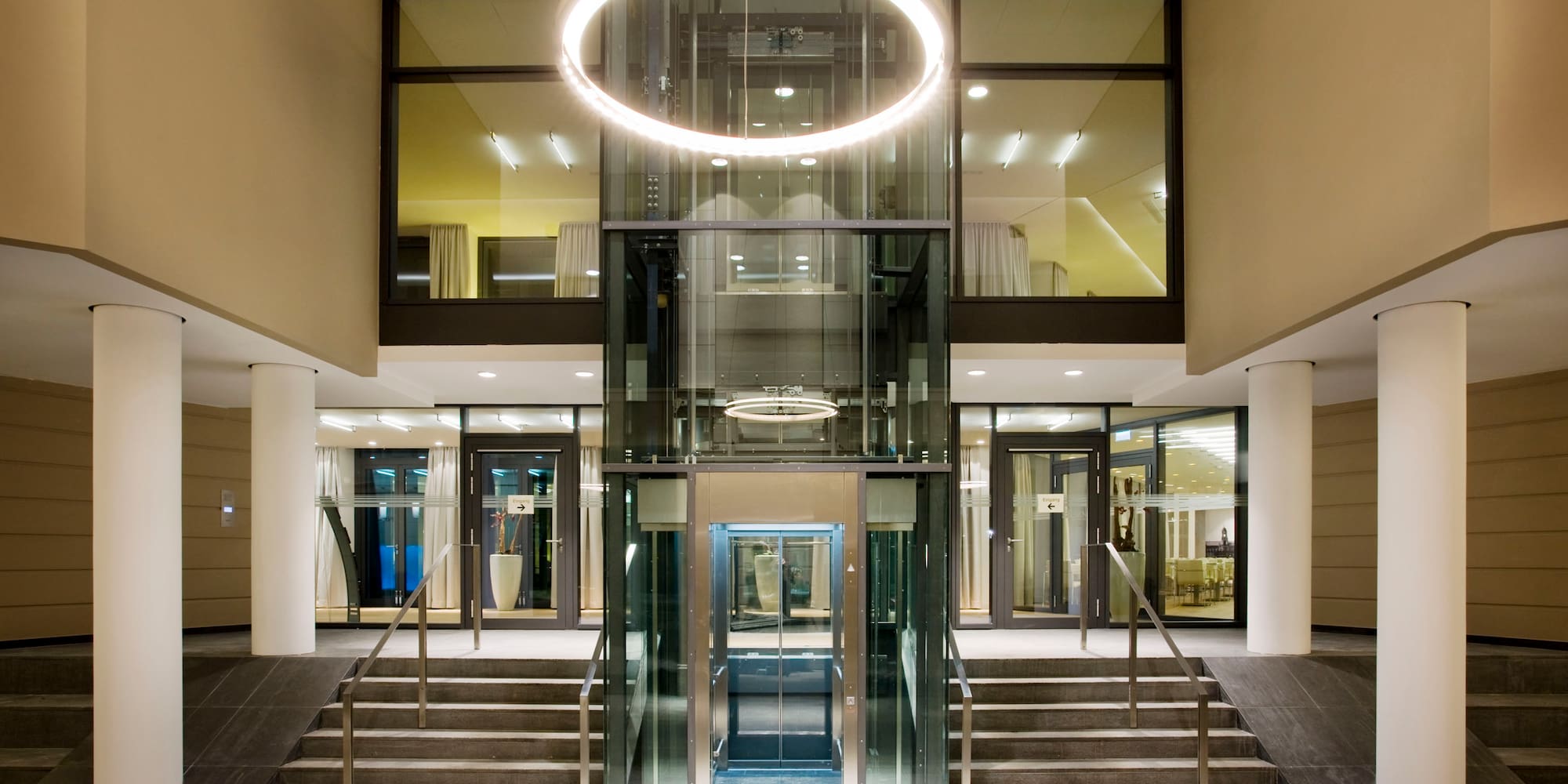 a glass elevator with a round light from the ceiling
