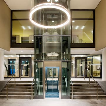 a glass elevator with a round light from the ceiling