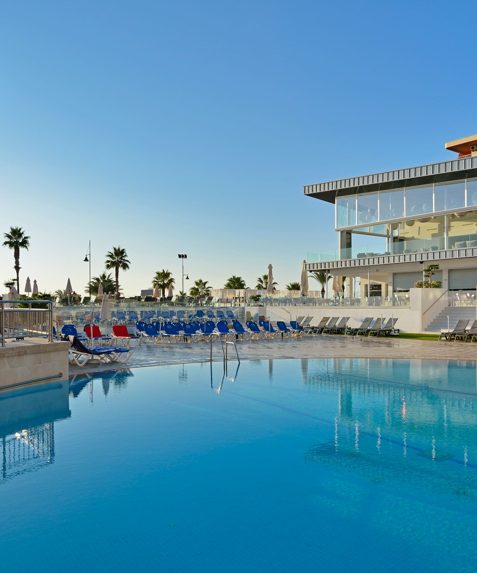 a pool with chairs and a building