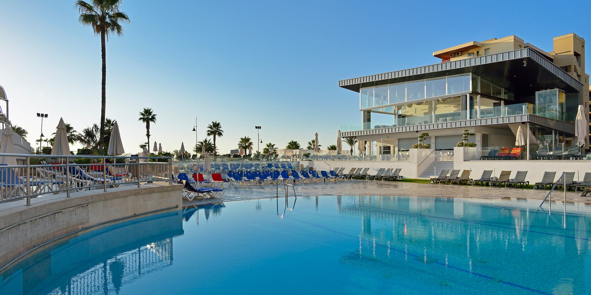 a pool with chairs and a building