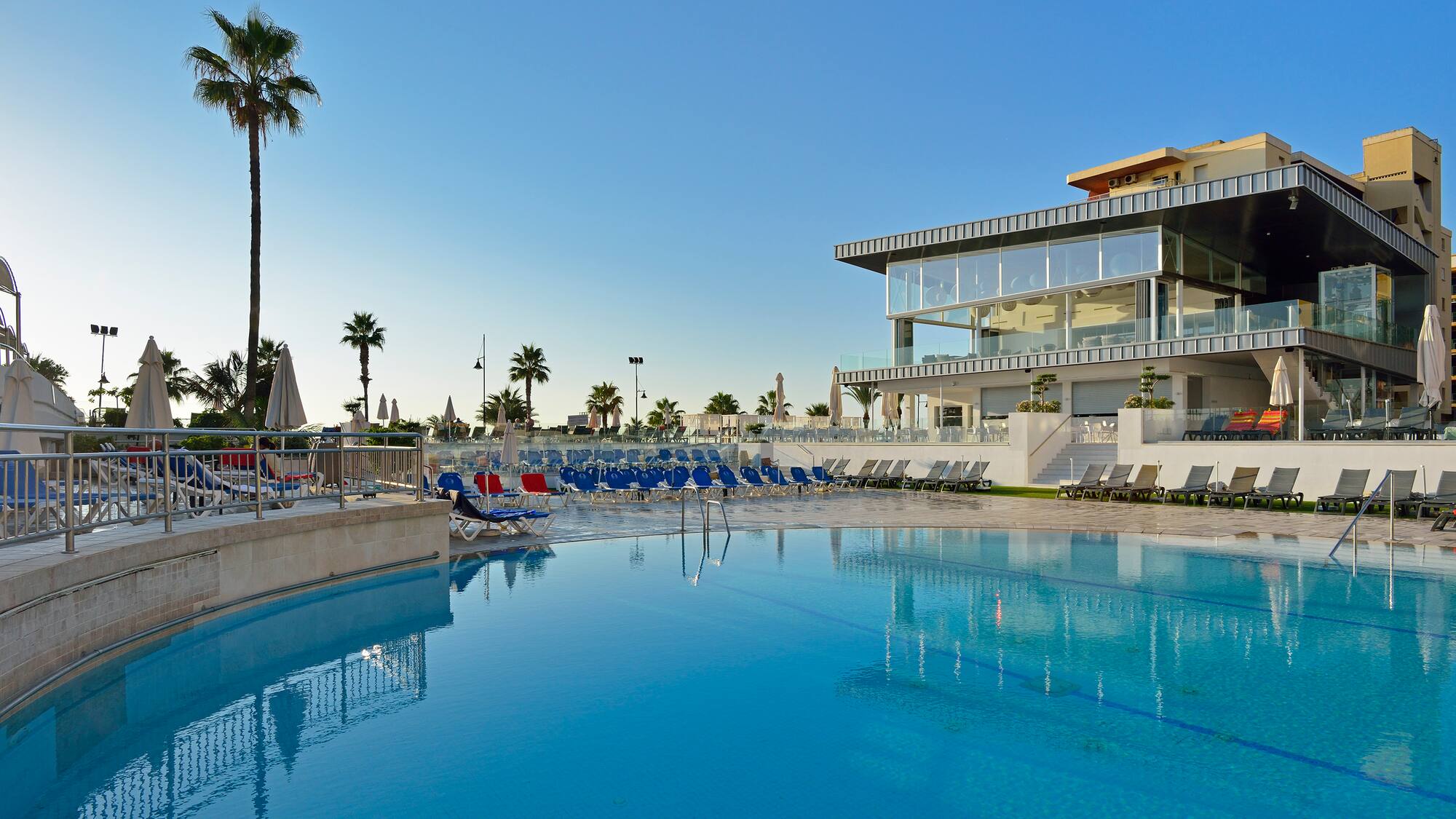 a pool with chairs and a building