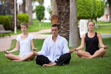 a group of people meditating in the grass