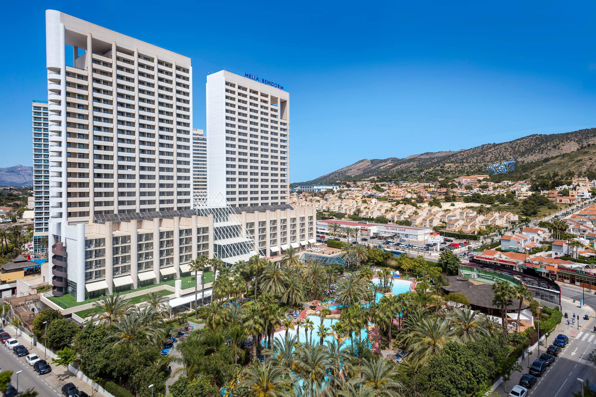 a large white building with palm trees and a pool