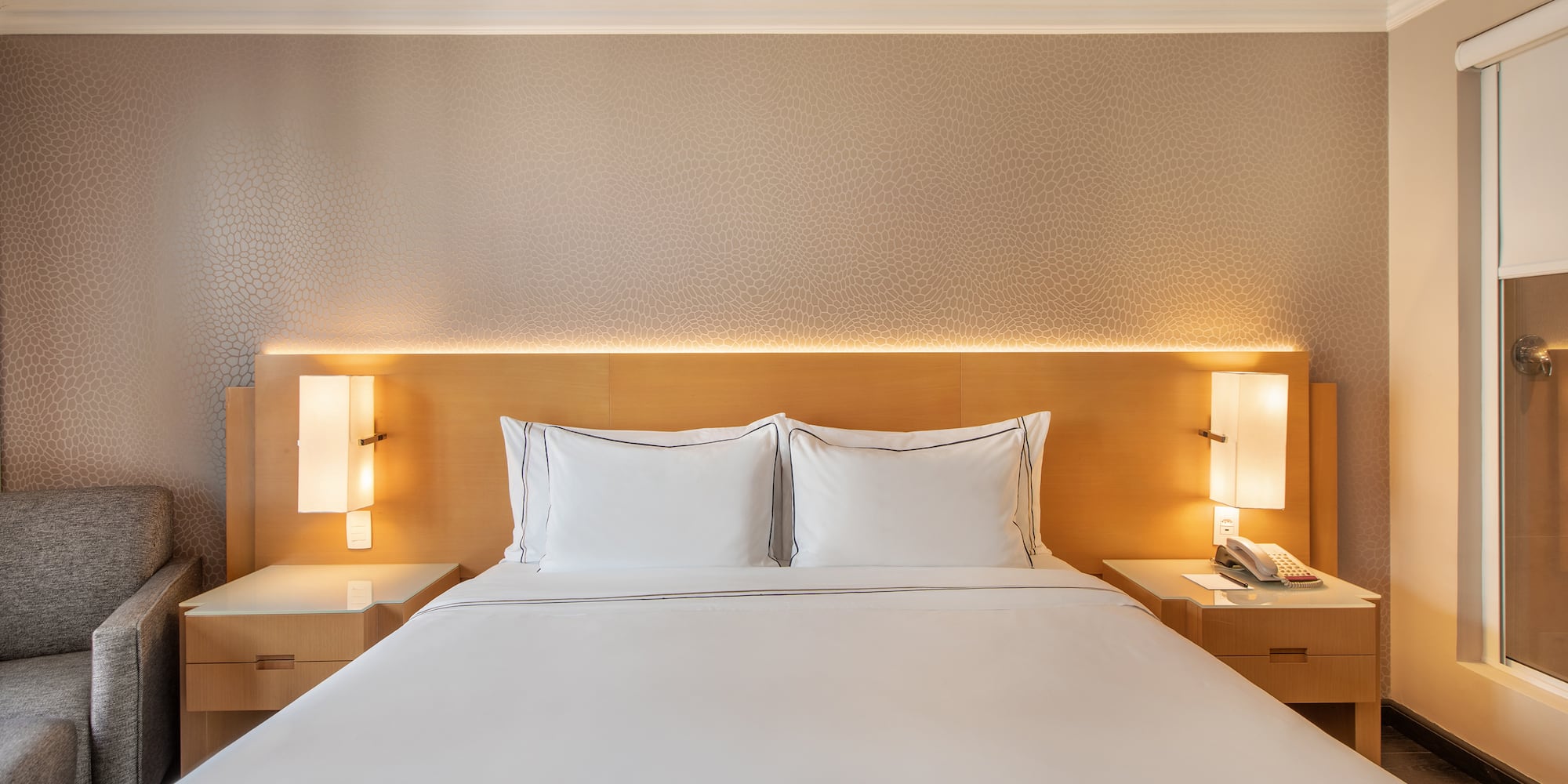 a bed with white sheets and a lamp on the side of it
