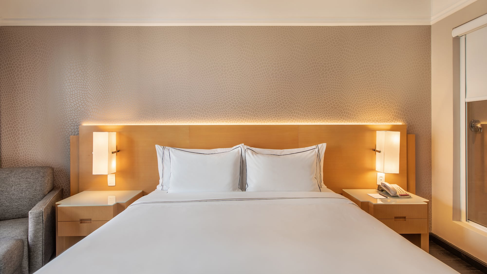 a bed with white sheets and a lamp on the side of it