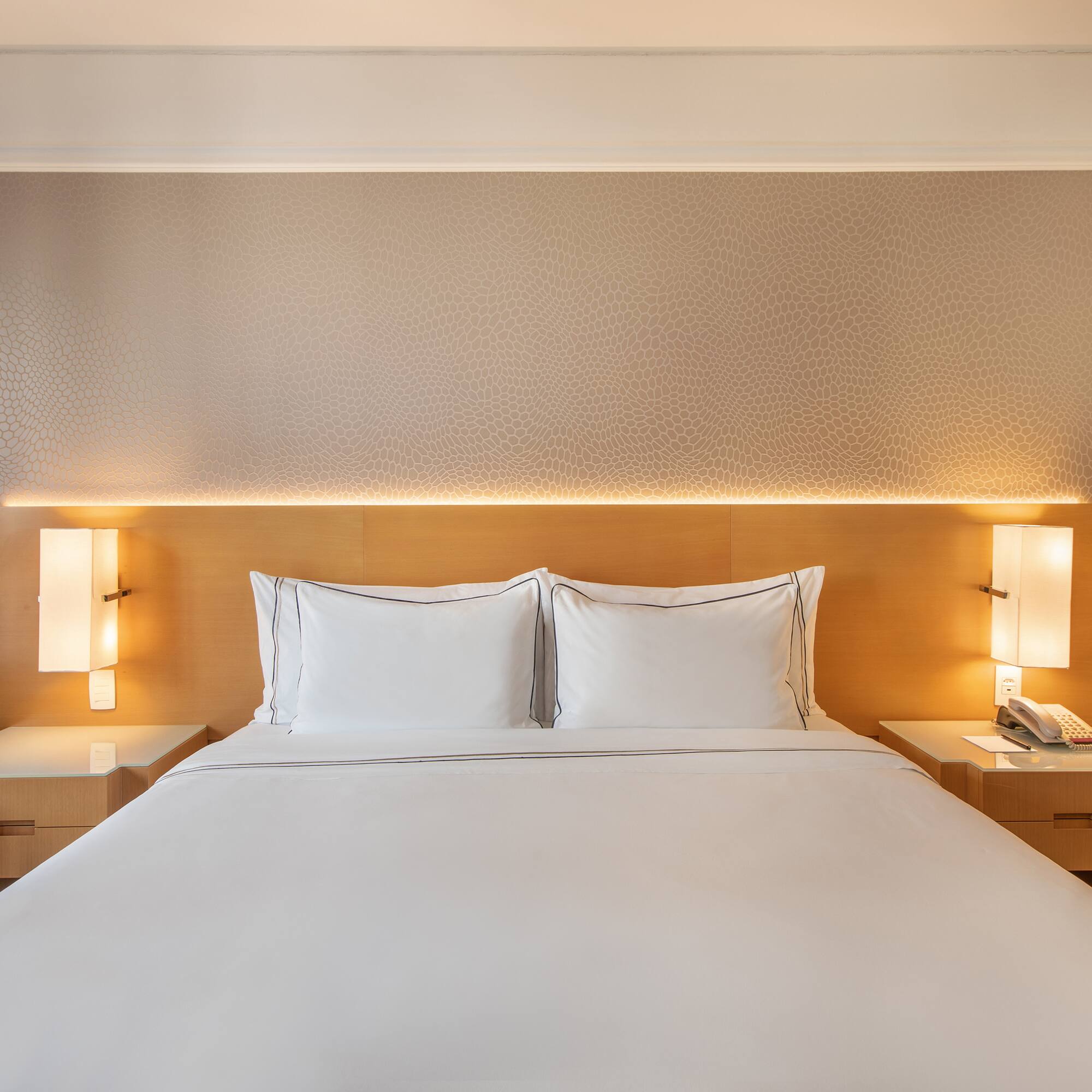 a bed with white sheets and a lamp on the side of it