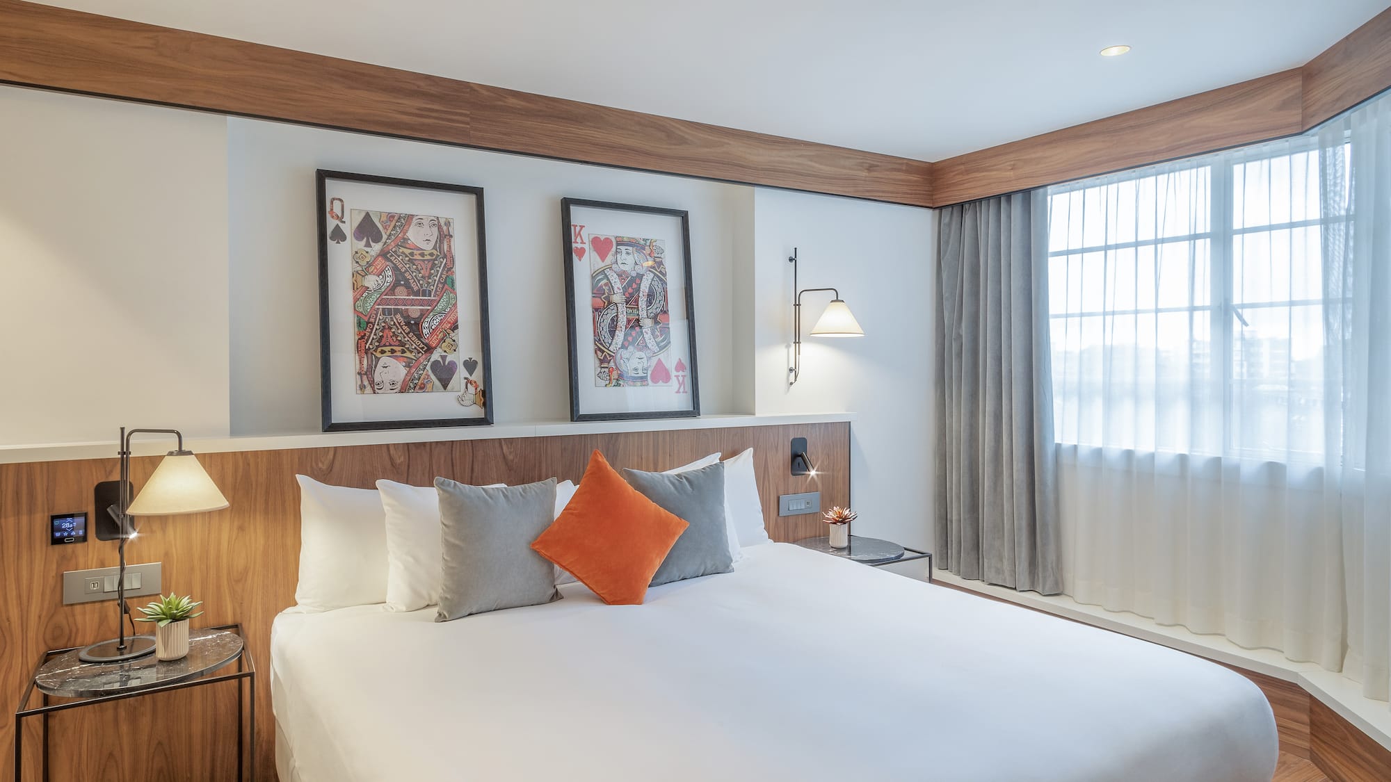 a bed with pillows and a table with two pictures on the wall