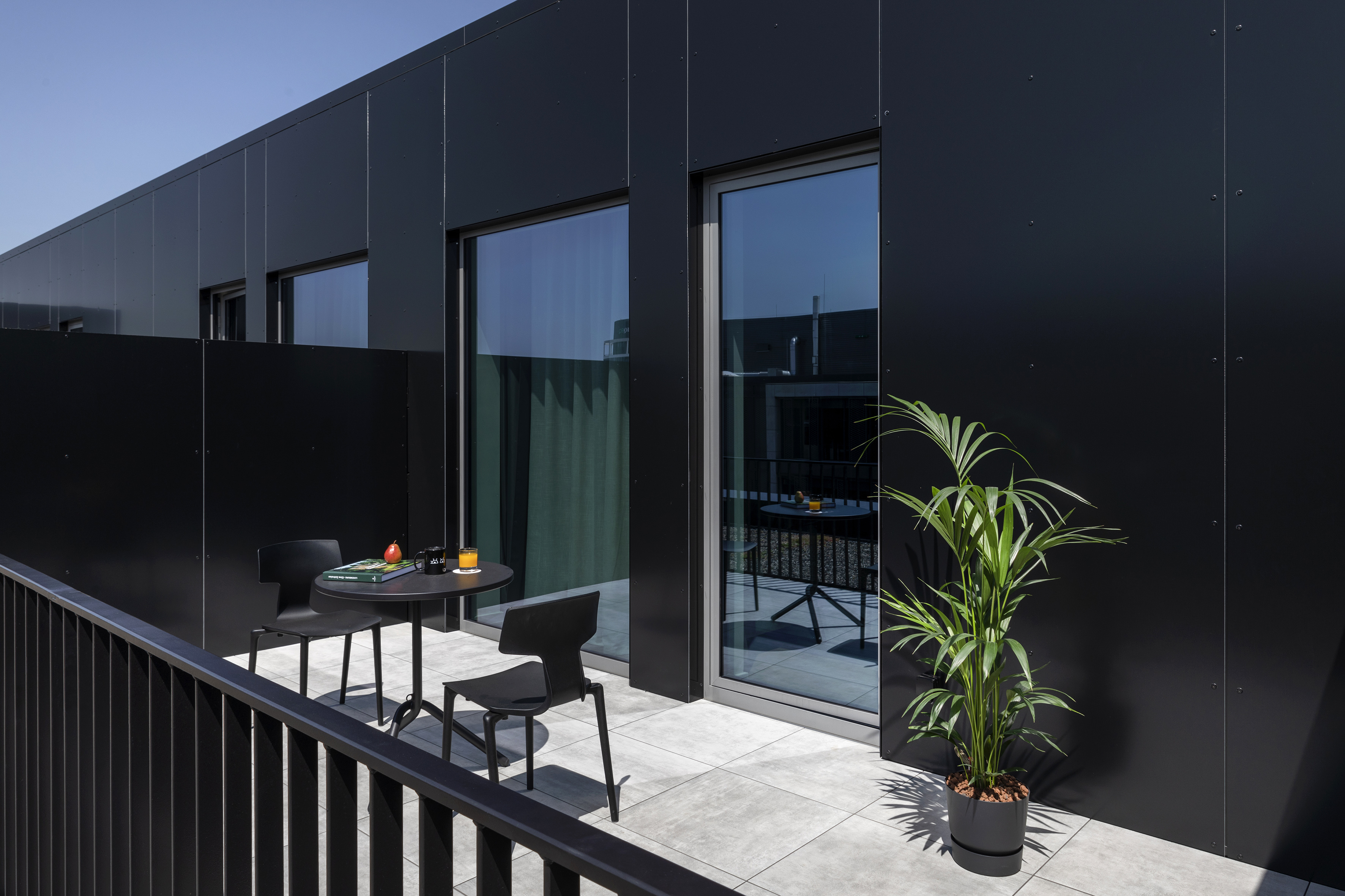 Contemporary black facade balcony with patio furniture and plant. - The Townhouse - INNSiDE Luxembourg, Luxemburg