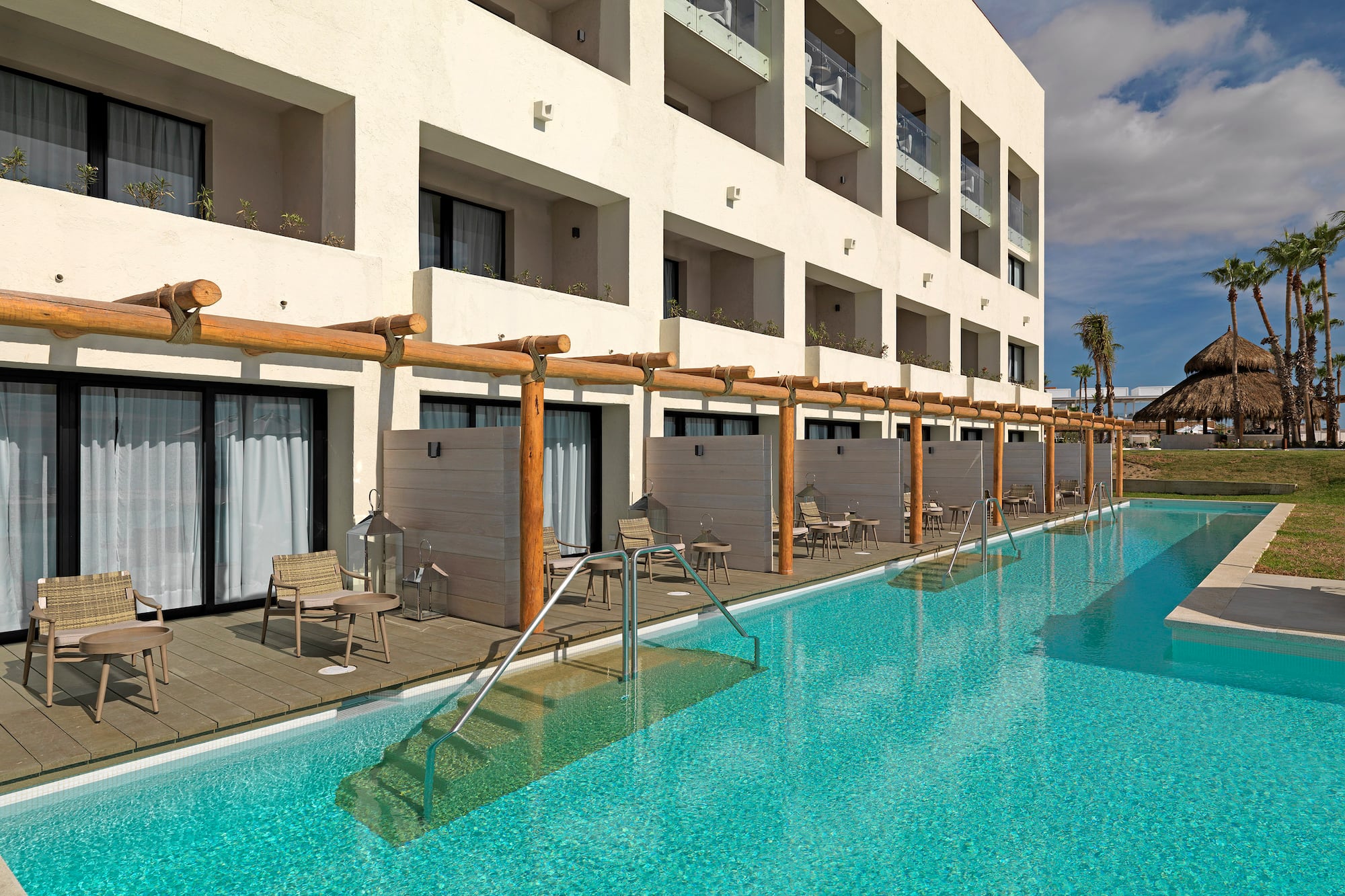 a pool with chairs and tables in front of a building