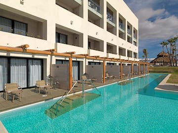 a pool with chairs and tables in front of a building