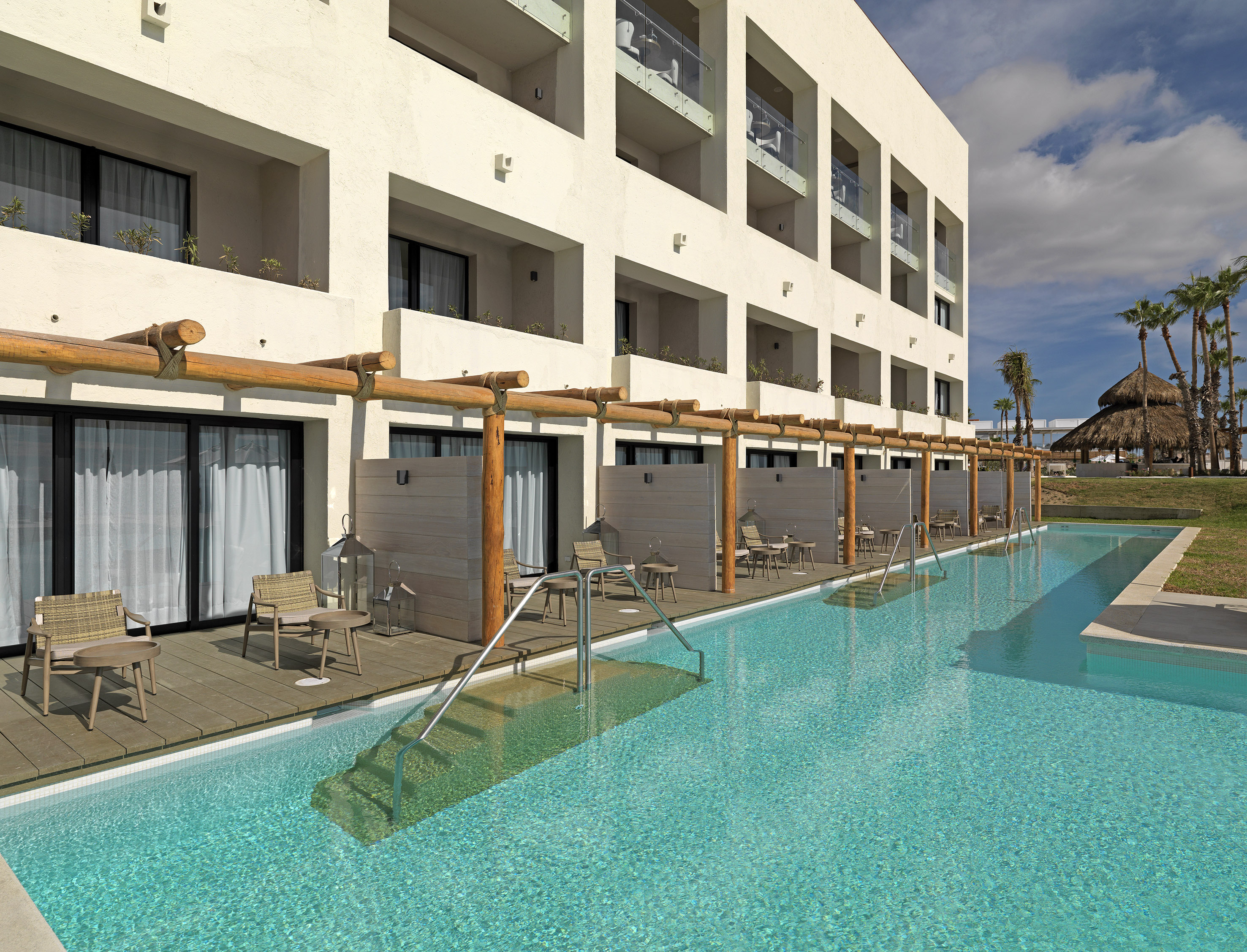 a pool with chairs and tables in front of a building