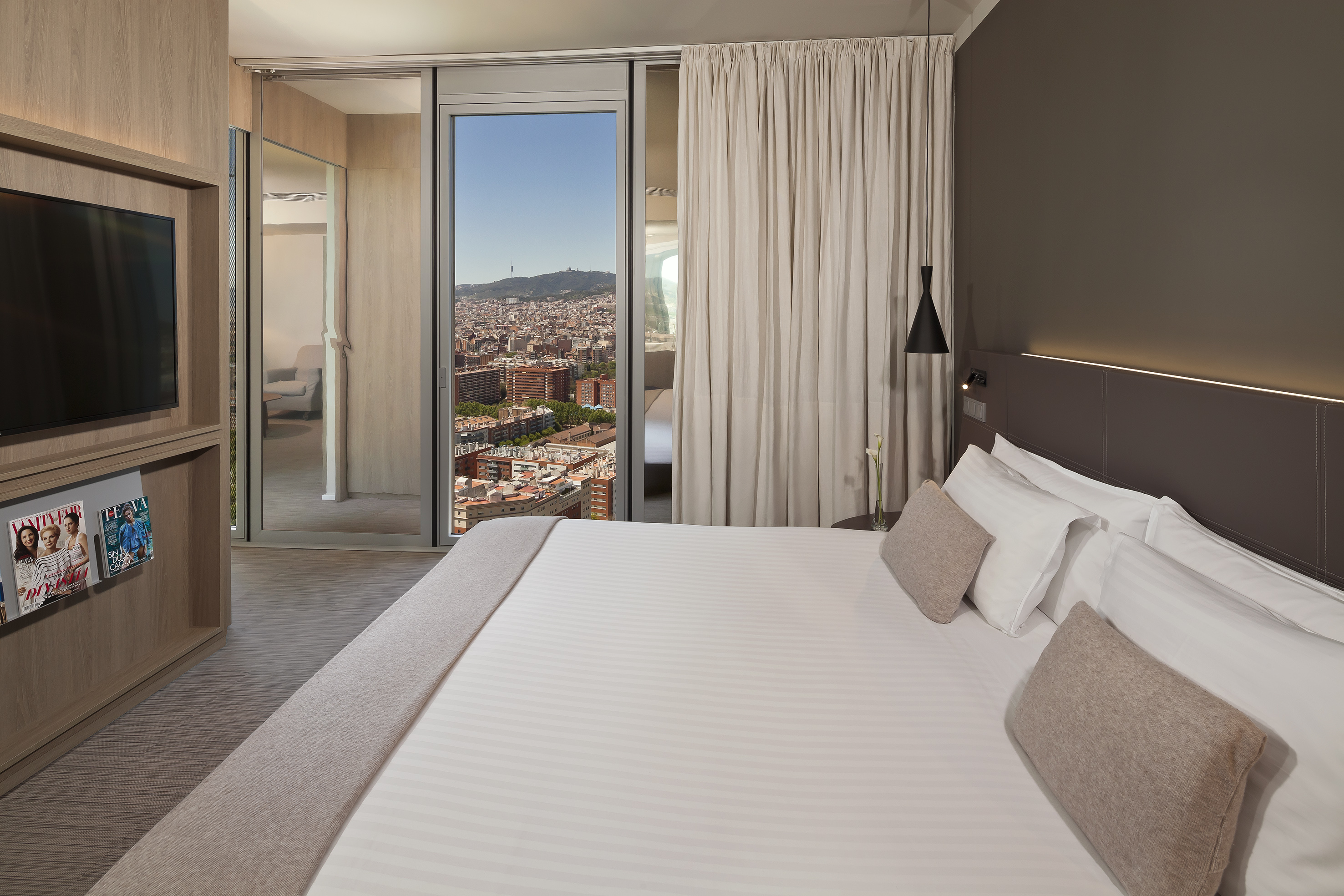 Modern hotel bedroom with comfortable bed and panoramic city views.