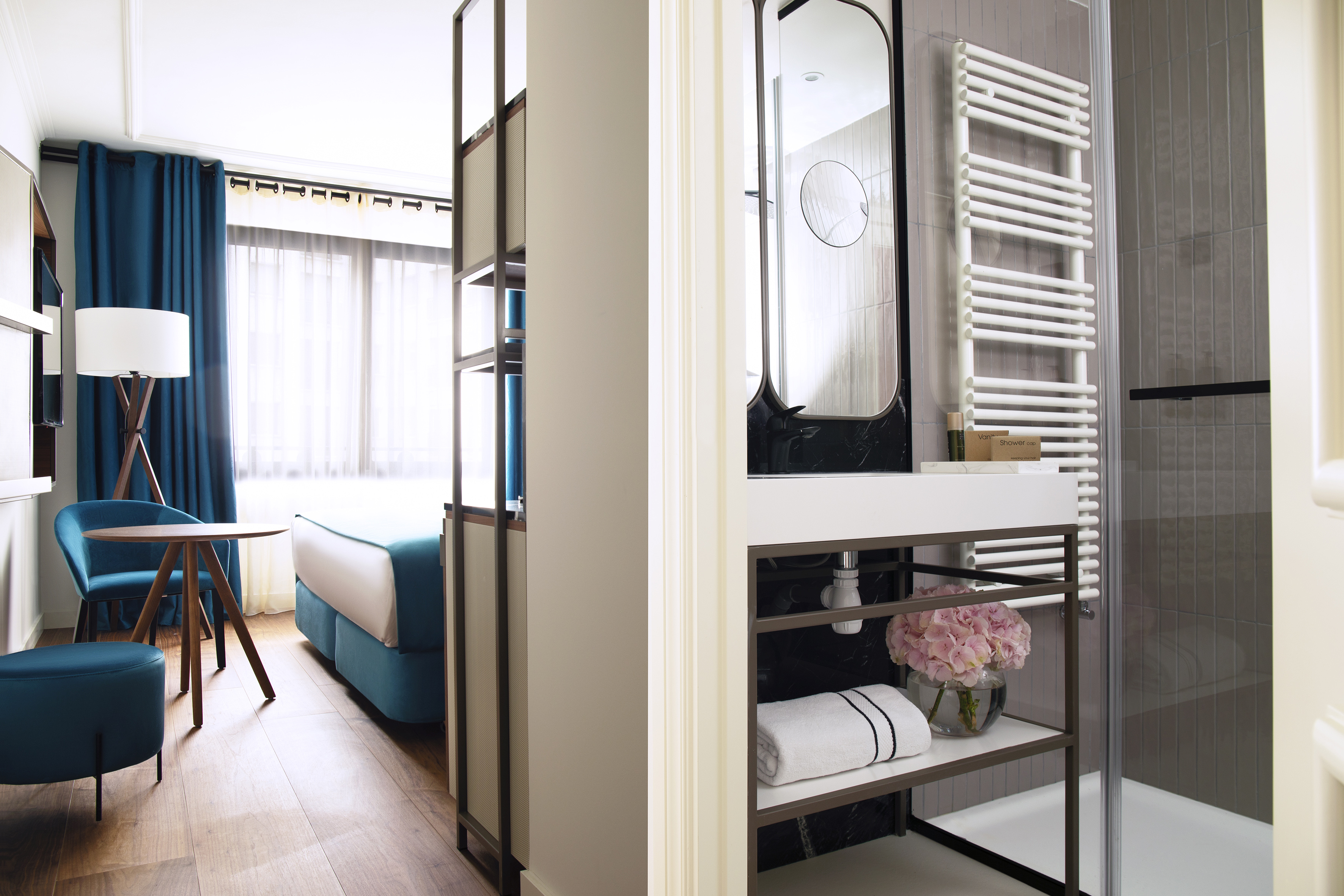 Modern hotel suite interior with blue bedroom and sleek bathroom.