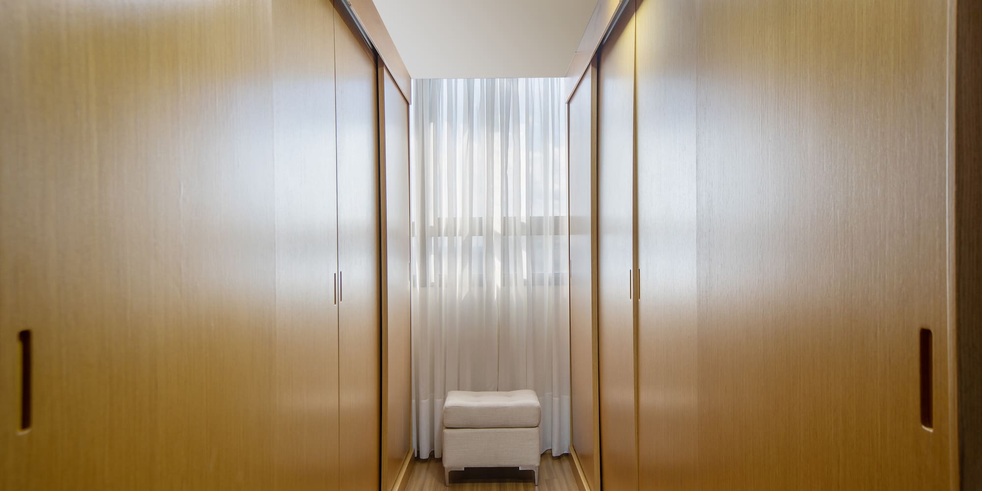 a room with a white stool and wooden cabinets