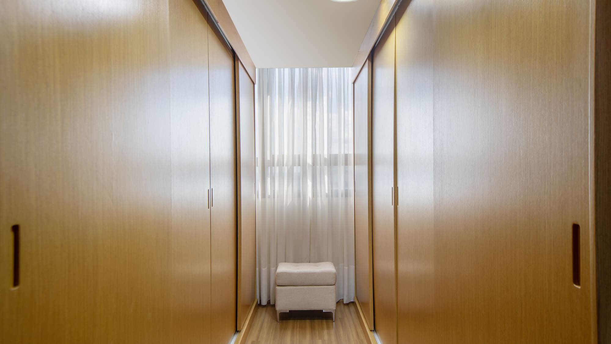 a room with a white stool and wooden cabinets