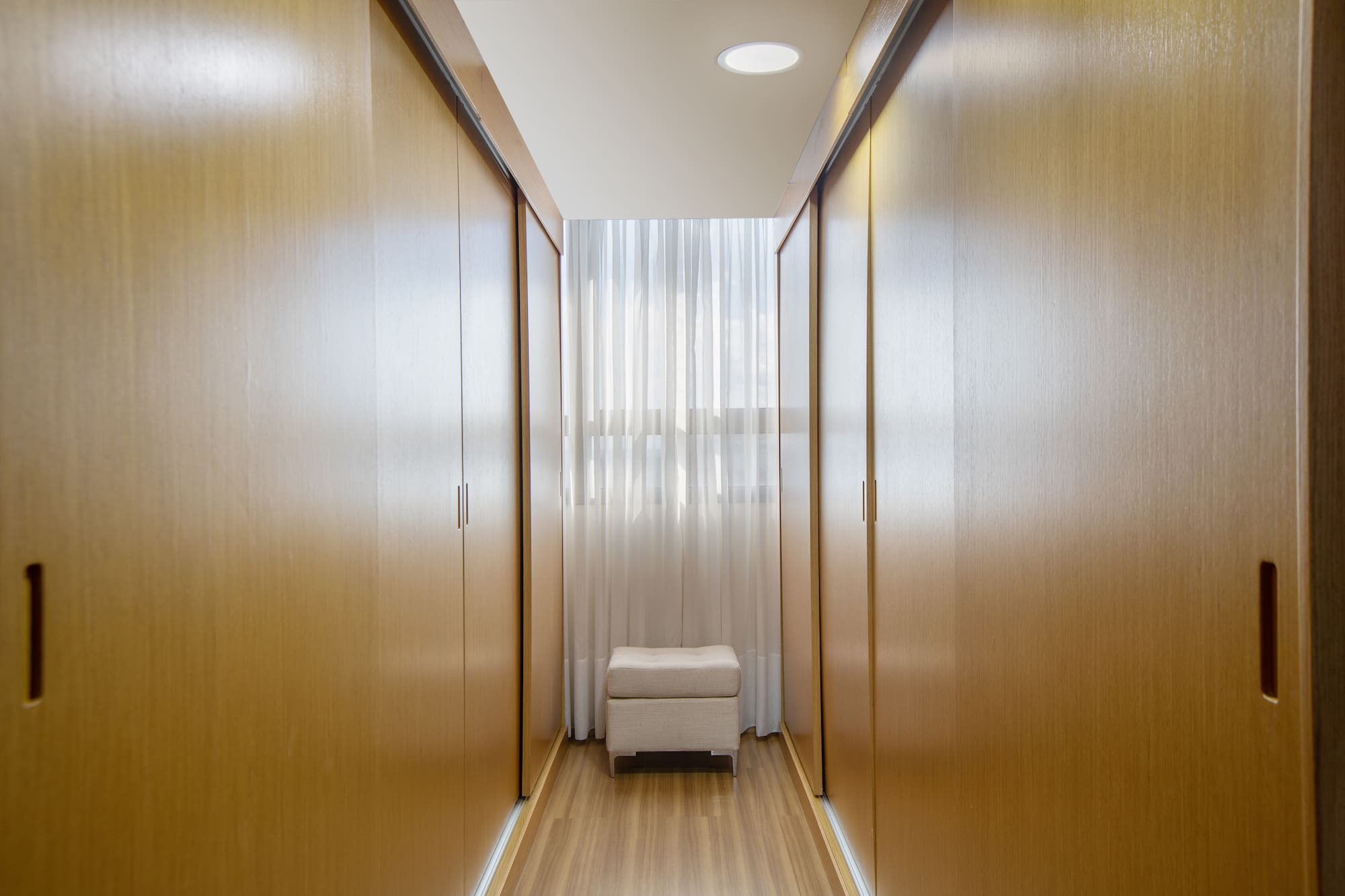 a room with a white stool and wooden cabinets