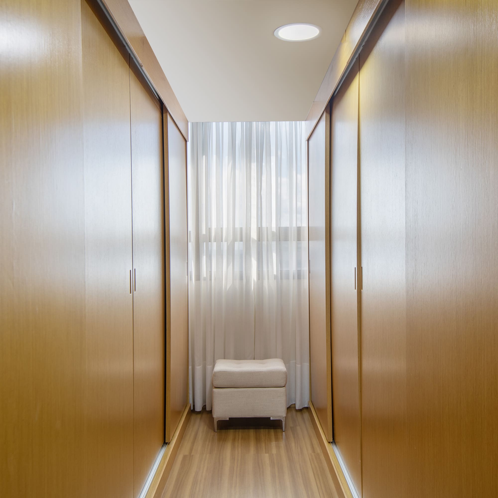 a room with a white stool and wooden cabinets
