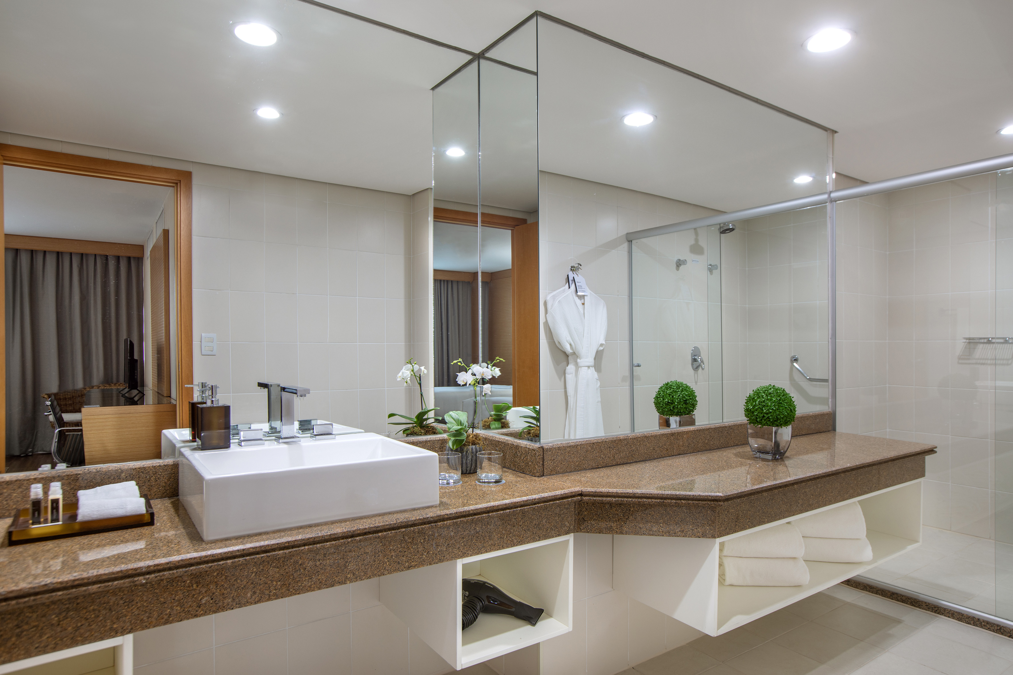 Hotel bathroom with vessel sink, granite vanity, large mirror, and glass shower.