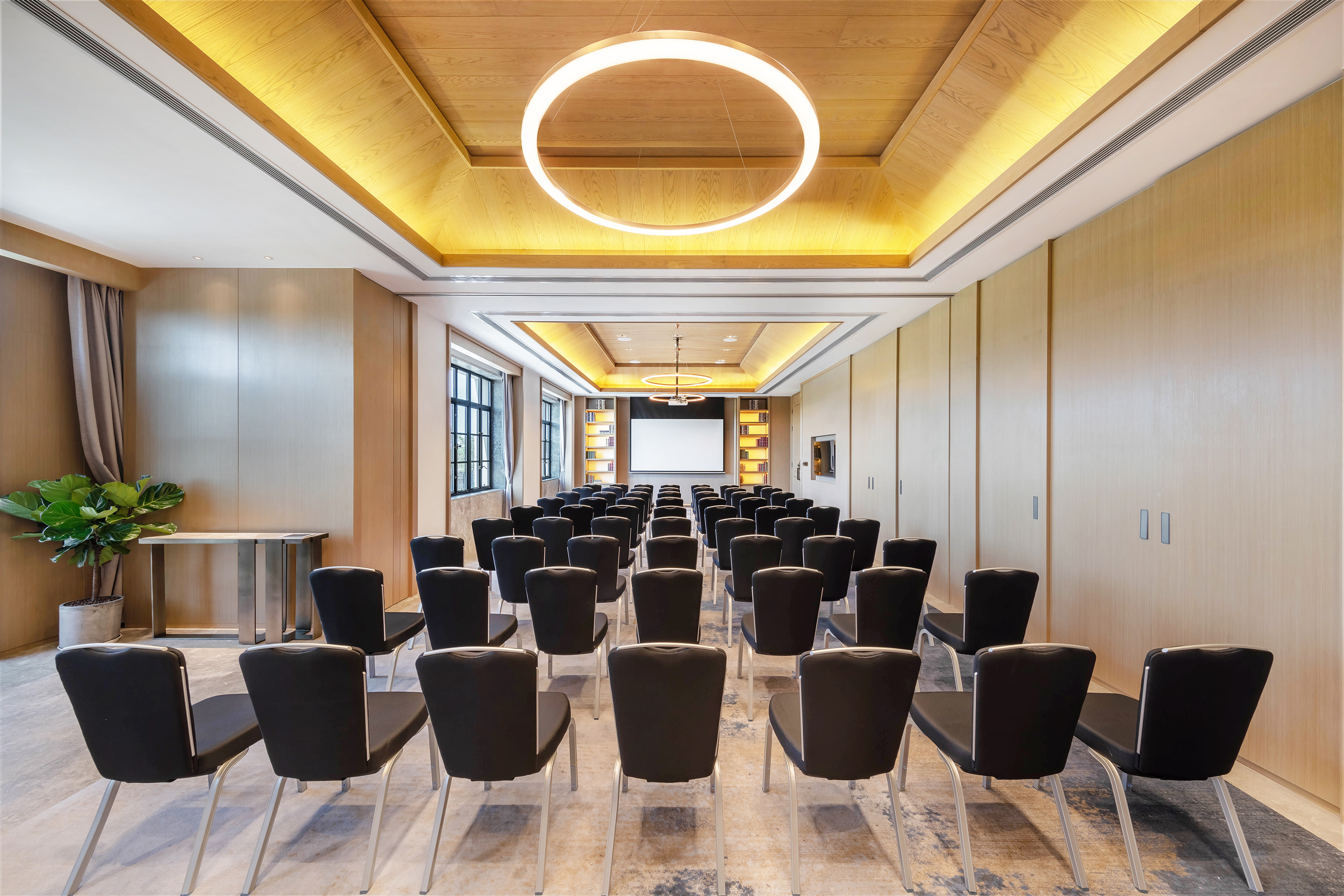 Modern conference room with black chairs, projection screen, and wood ceiling.