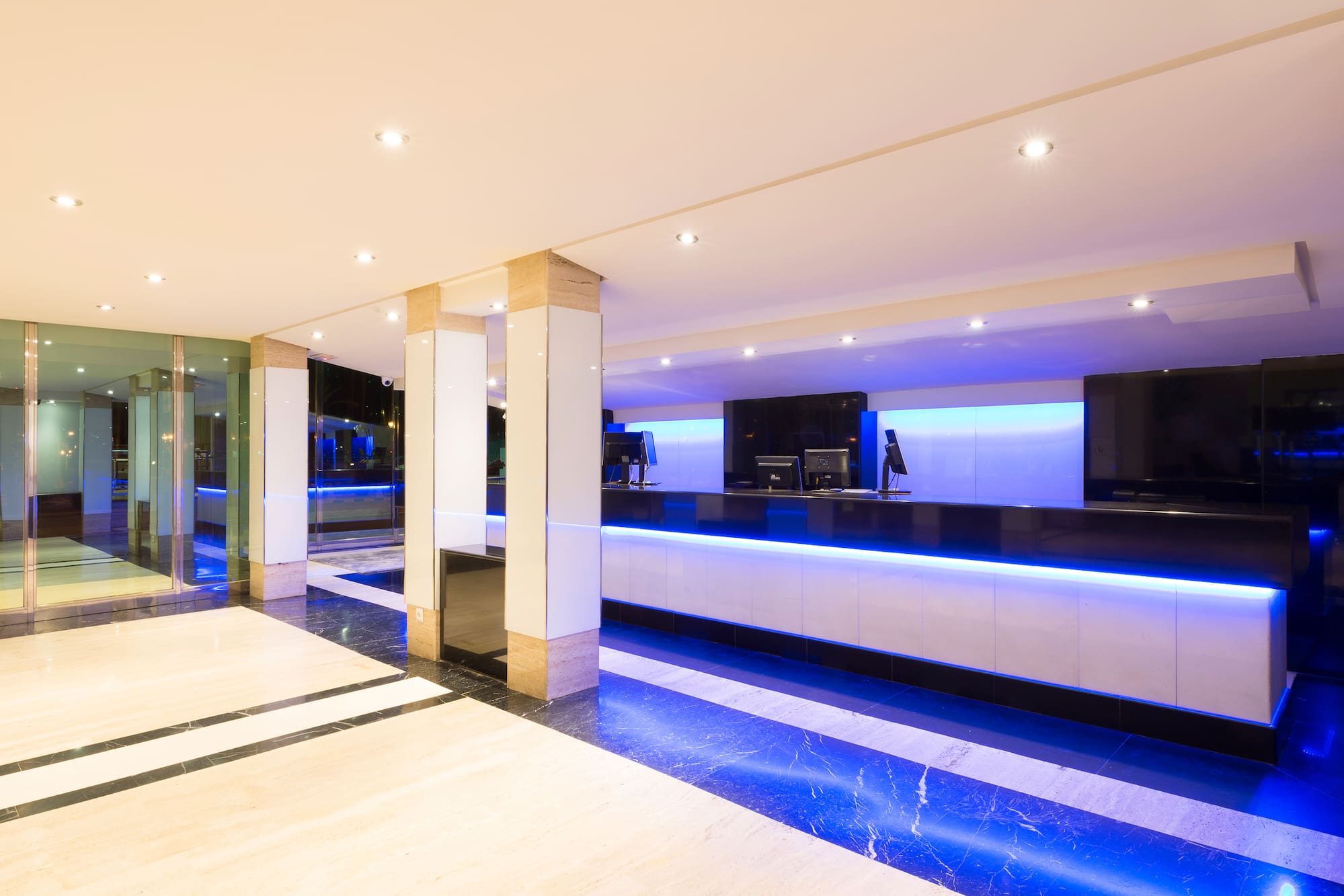 Modern hotel reception desk with blue LED lighting and sleek marble floor.