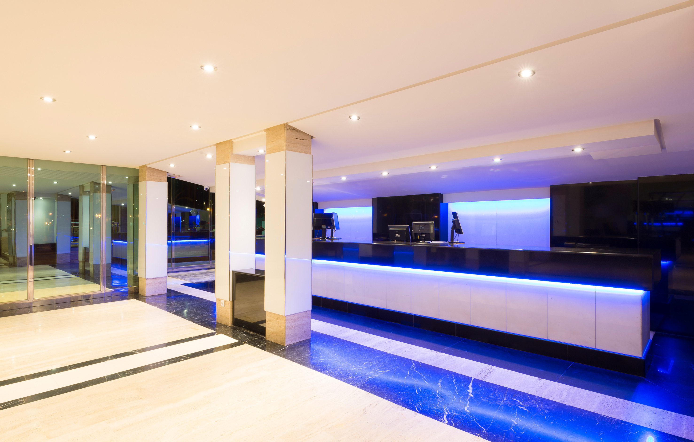 Modern hotel reception desk with blue LED lighting and sleek marble floor.