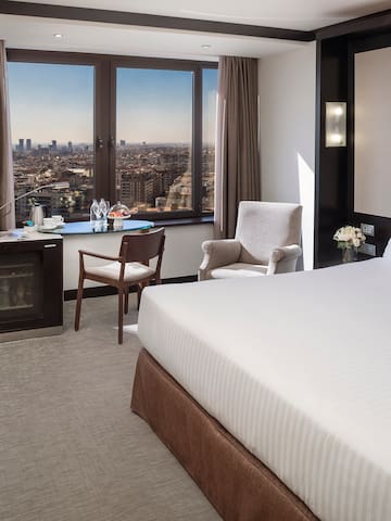 a room with a large bed and a window with a city view