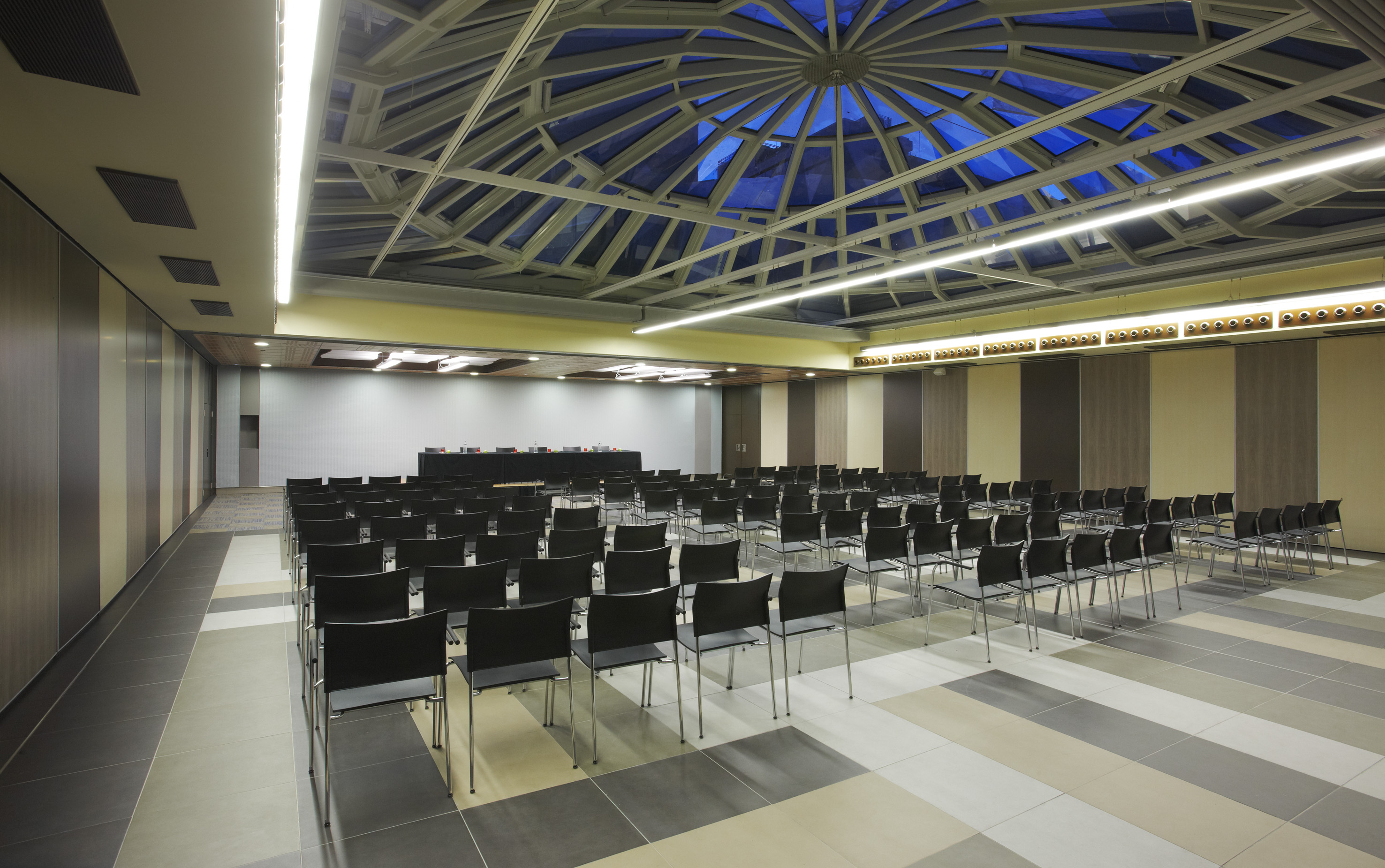 Modern conference room with black chairs and domed glass ceiling.