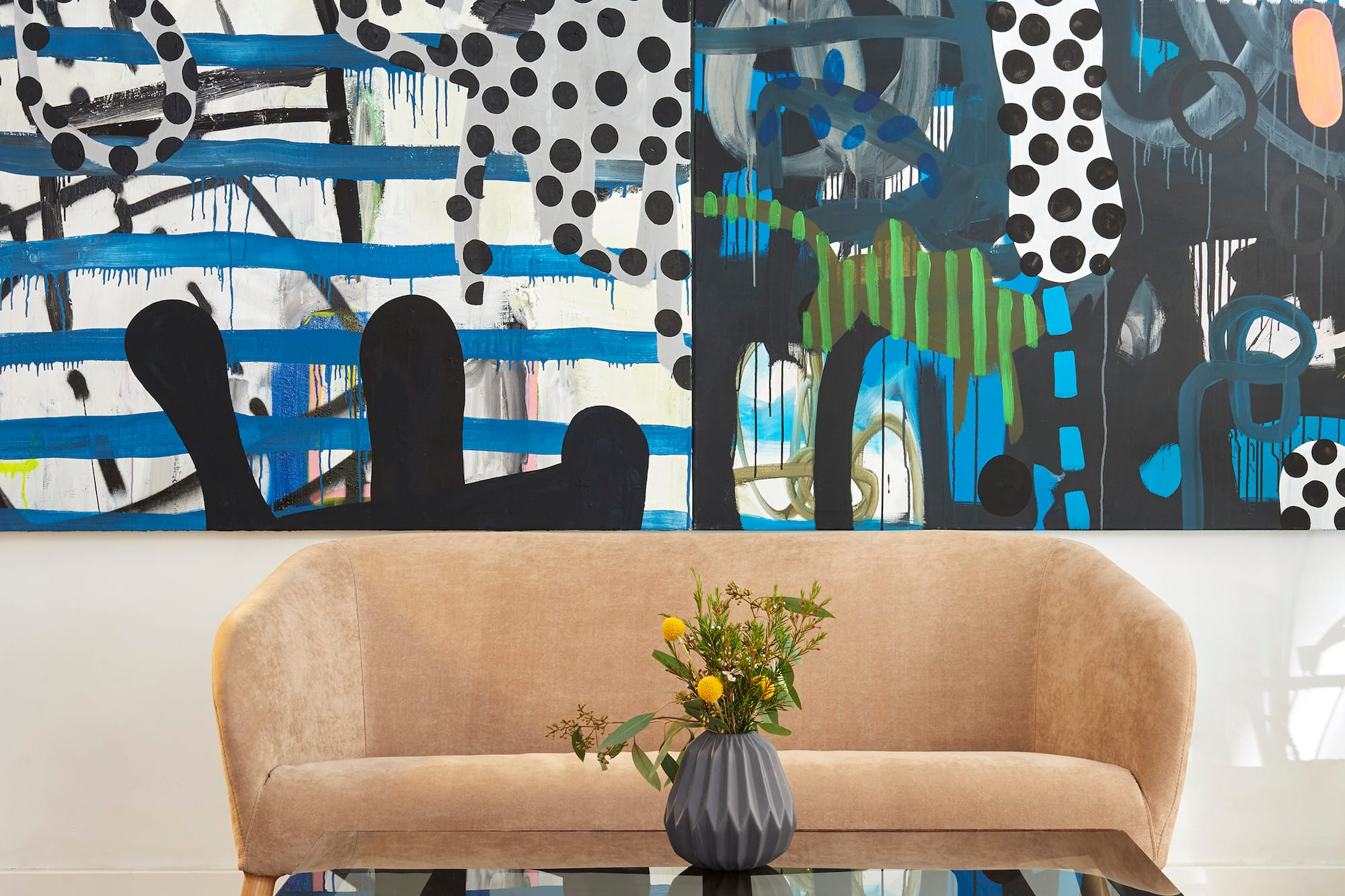 Modern living room with vibrant abstract art, beige sofa, wood coffee table, geometric rug.