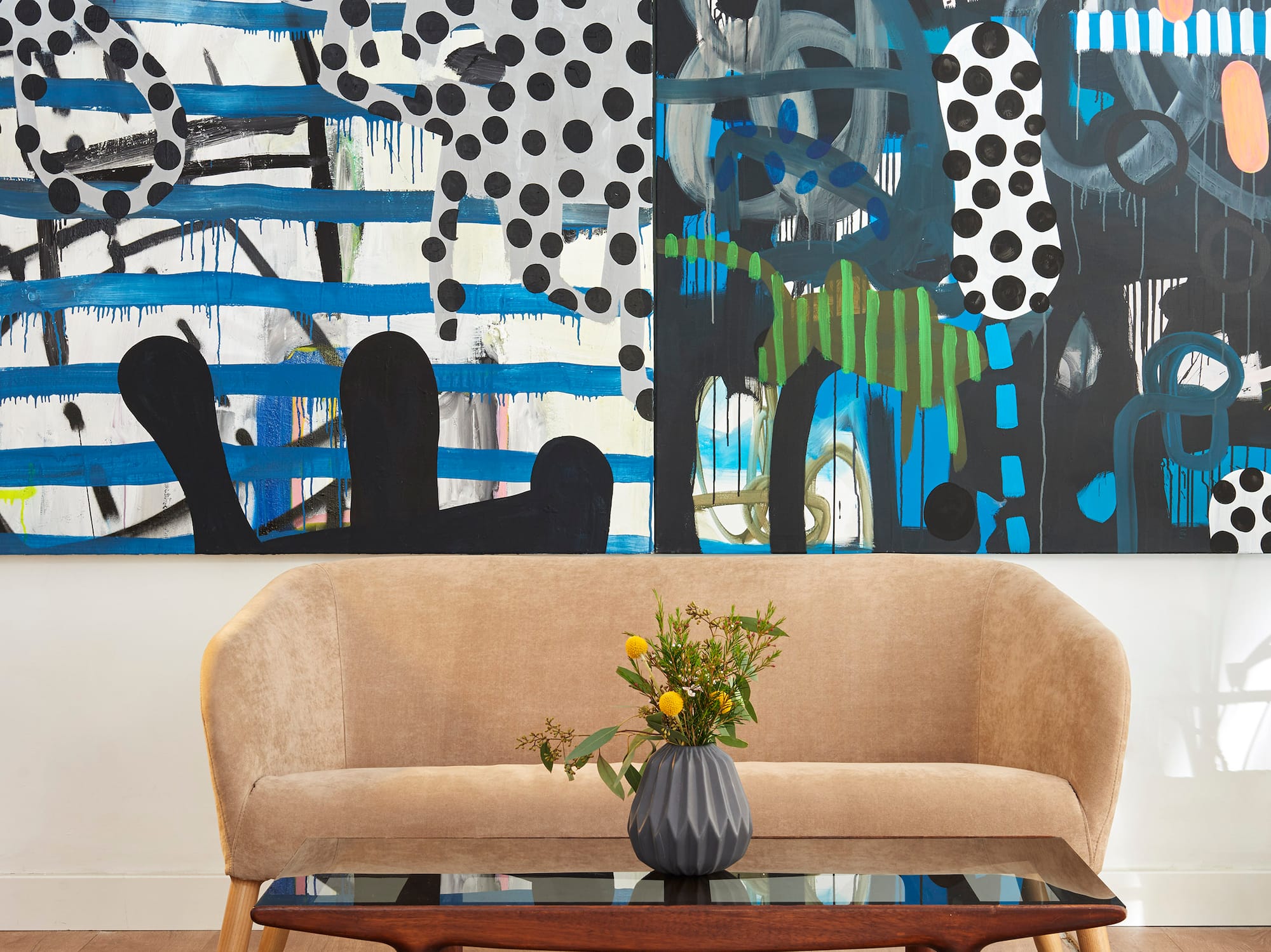 A couch and a coffee table sit in front of a painting.