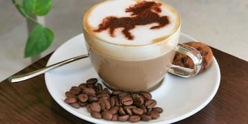 a cup of coffee with a horse design on top of it