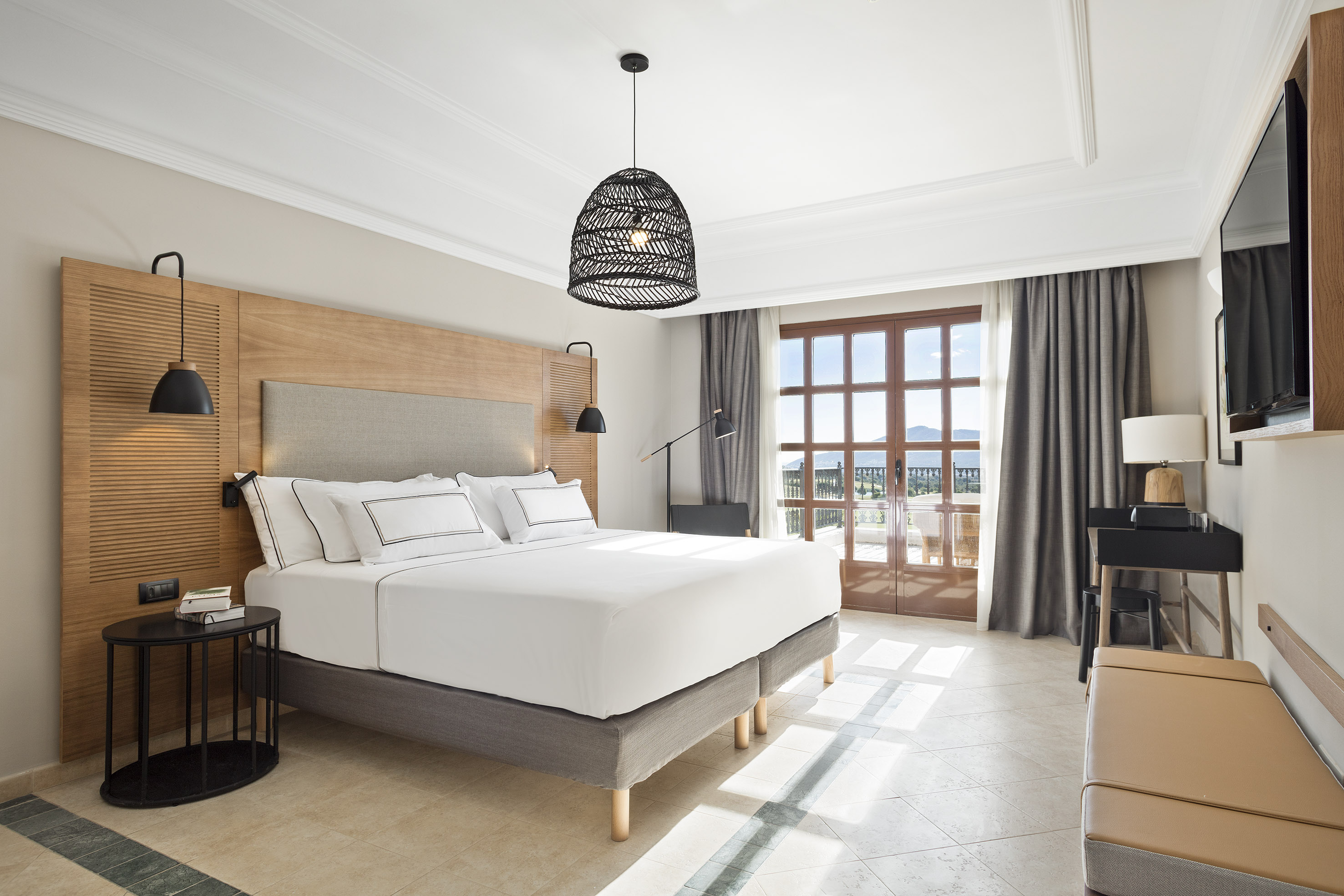Contemporary hotel room with king bed, balcony mountain view, and elegant decor.