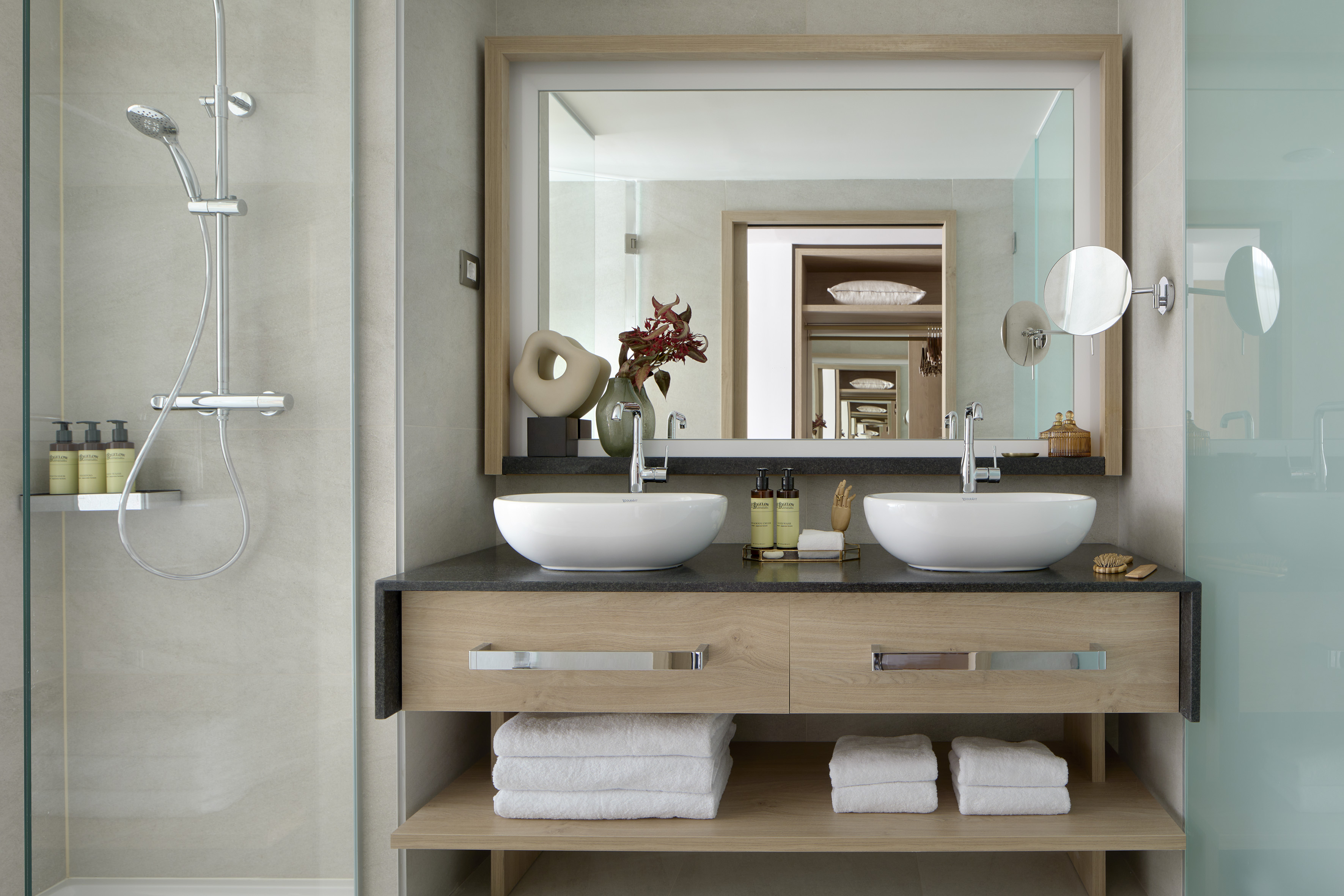 Modern bathroom with double vanity, shower, and large mirror.