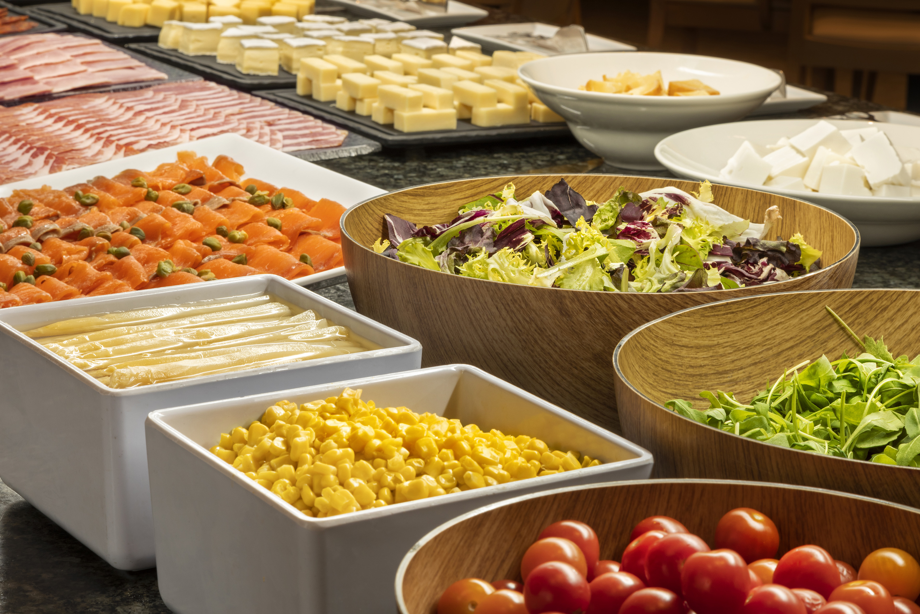 Buffet with smoked salmon, fresh mixed salads, various cheeses, and vegetables.