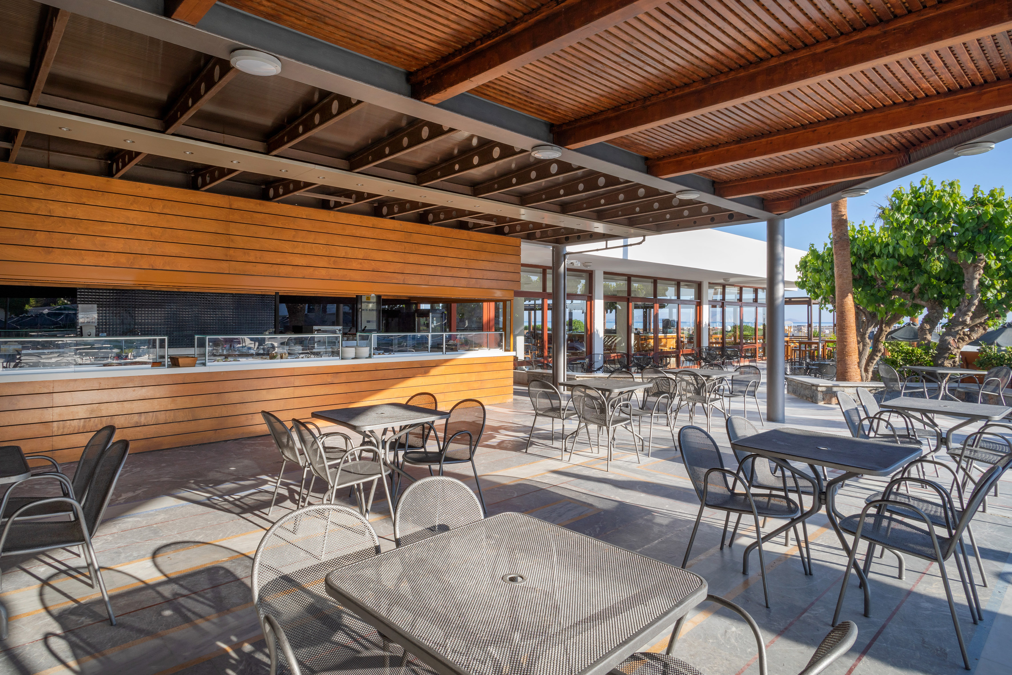 Spacious covered outdoor restaurant patio with metal furniture and buffet.